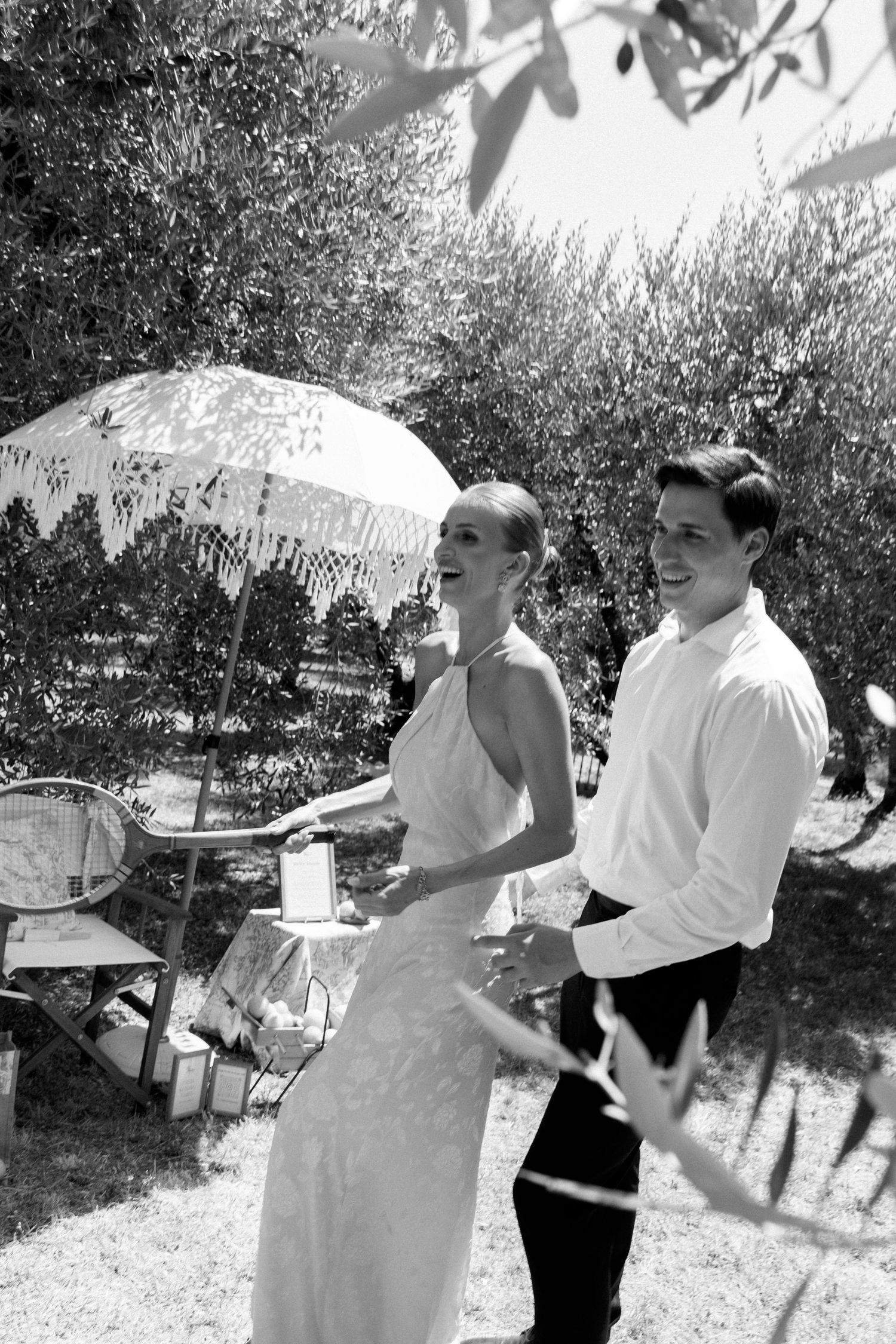 A playful outdoor celebration scene with guests in white and black attire.