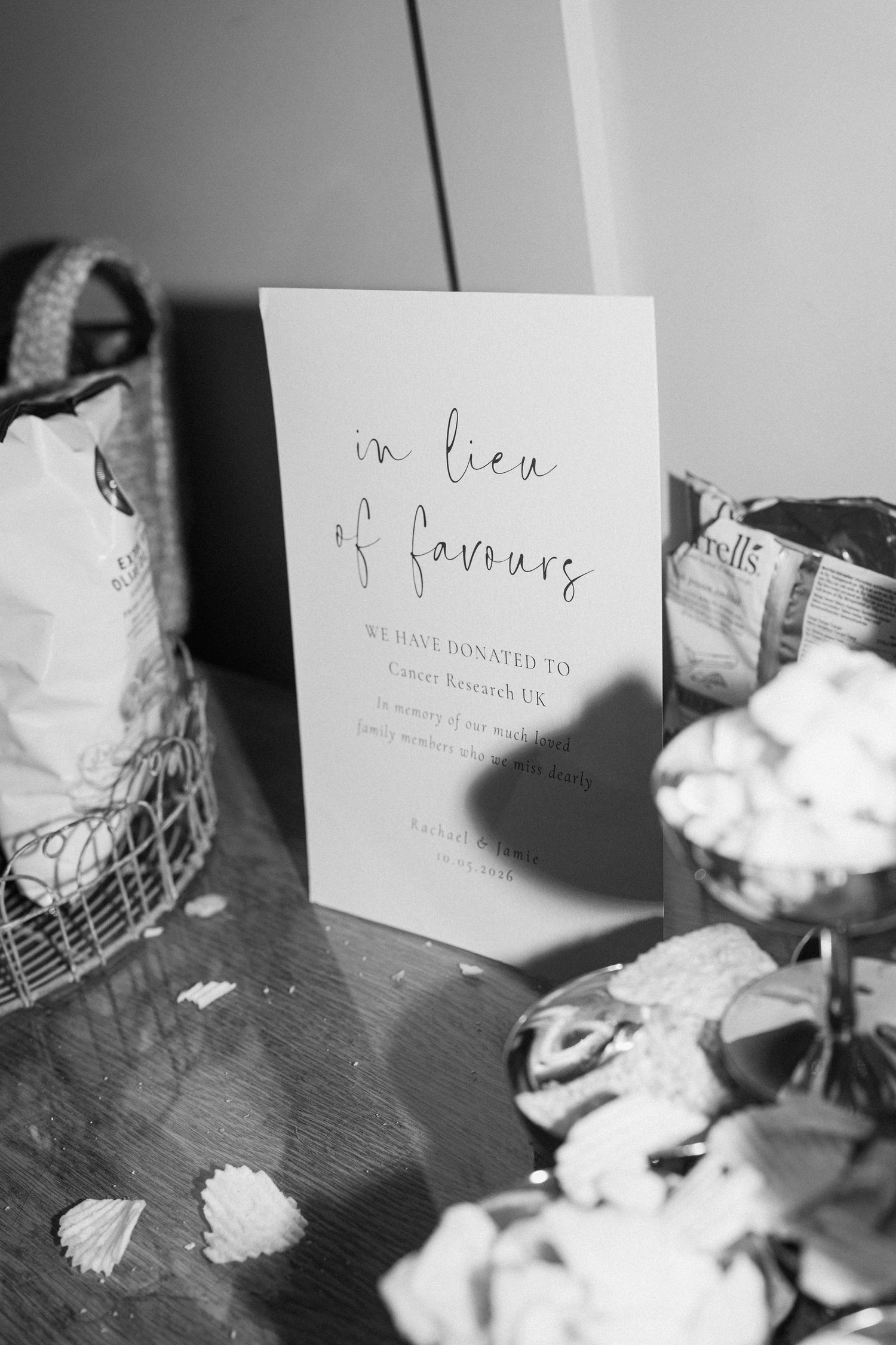 Black and white photo of a wedding sign reading in lieu of favours with a donation to Cancer Research UK.