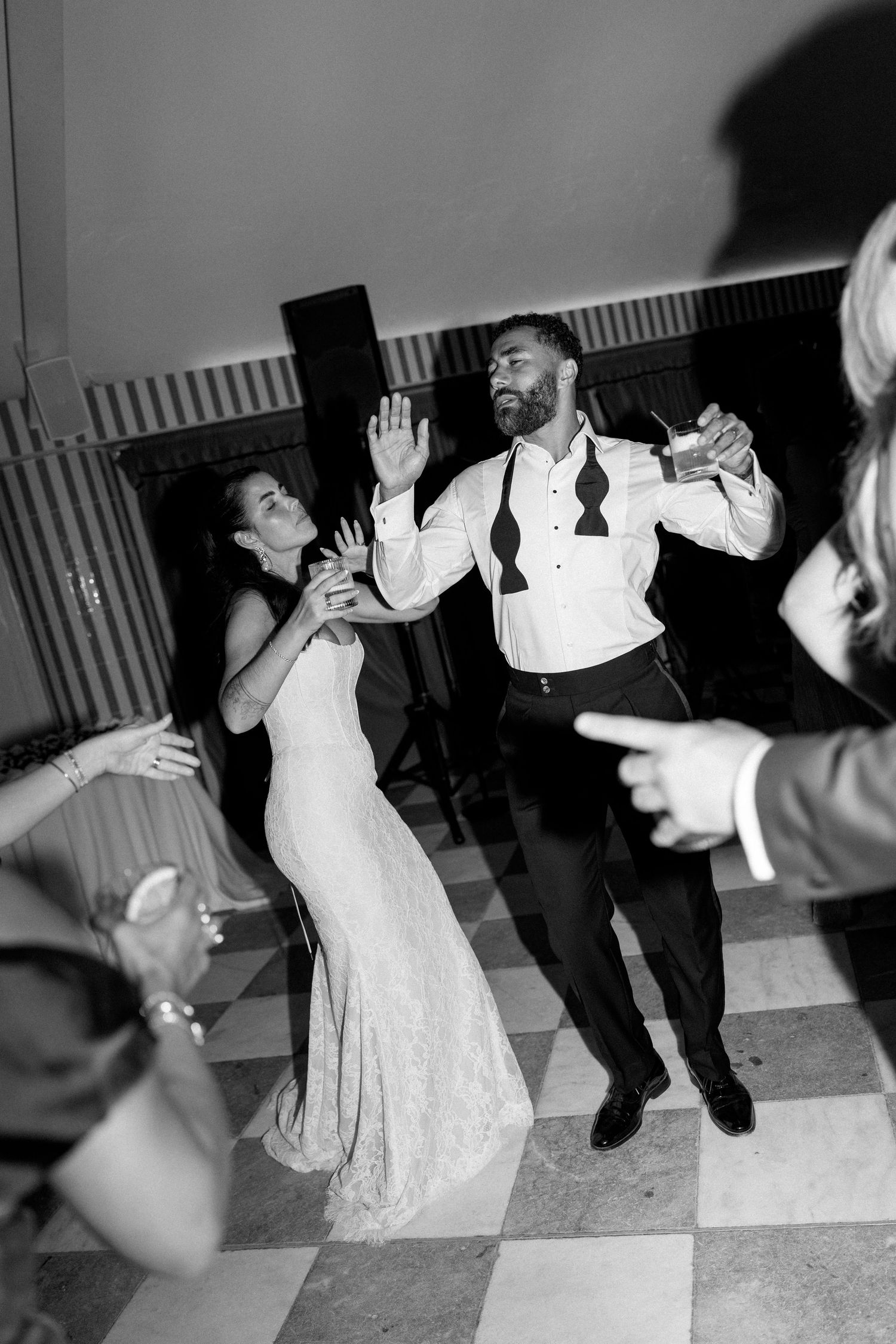 Bride and groom dancing joyfully on a checkered dance floor during their wedding reception.