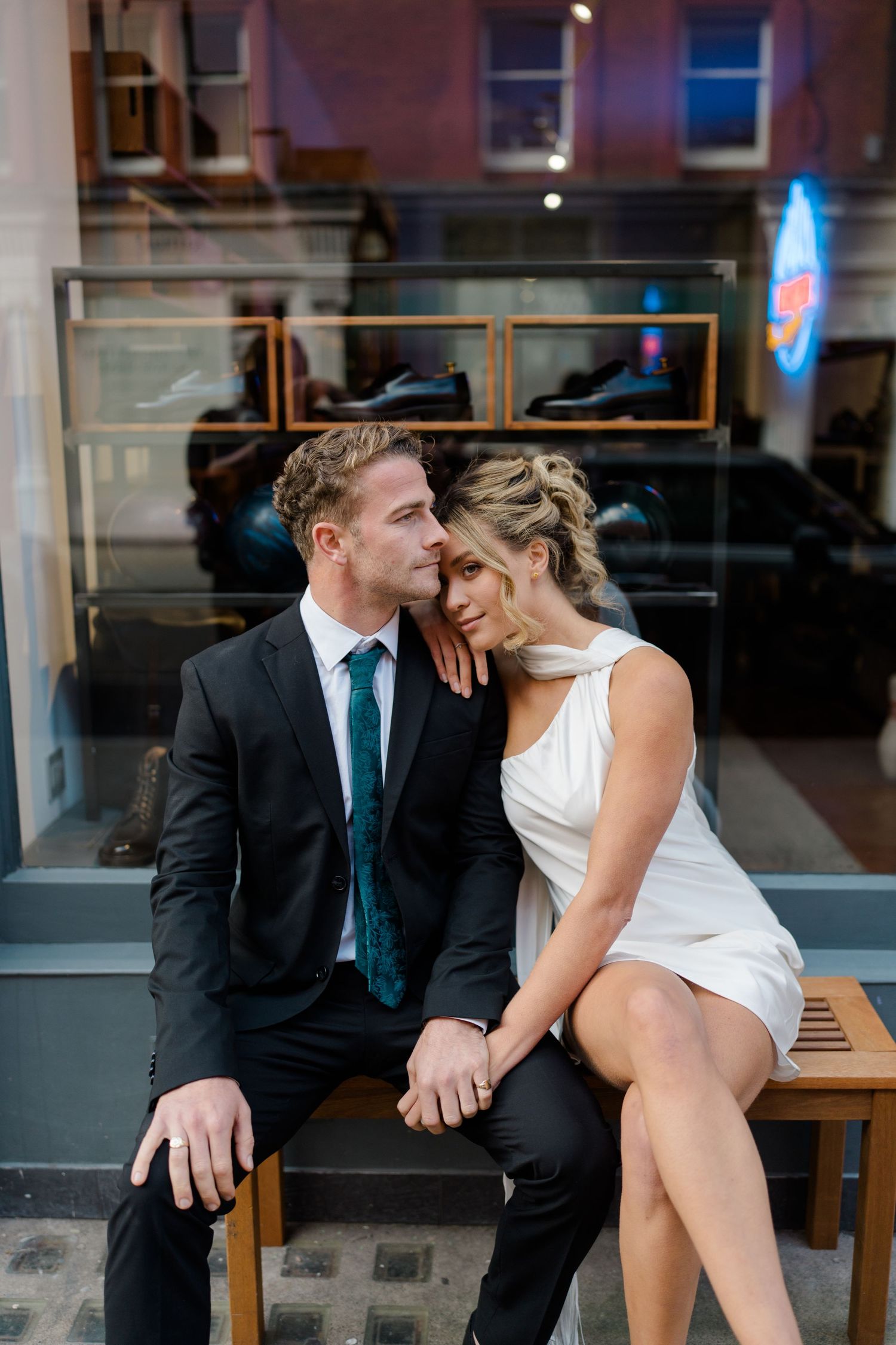 Romantic couple shares intimate moment on wooden bench in evening light.