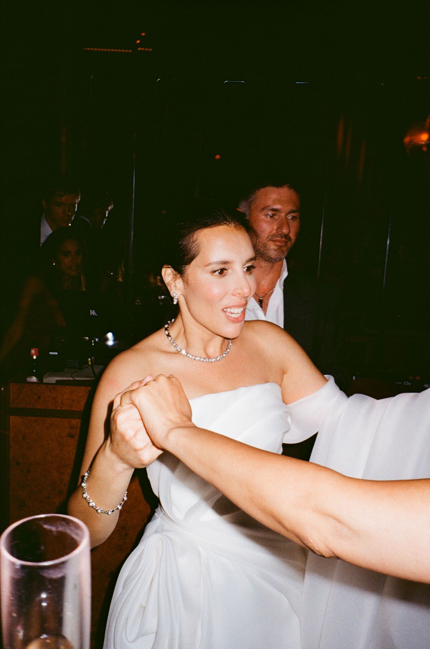 People dancing and celebrating at a dimly lit indoor party or reception venue.