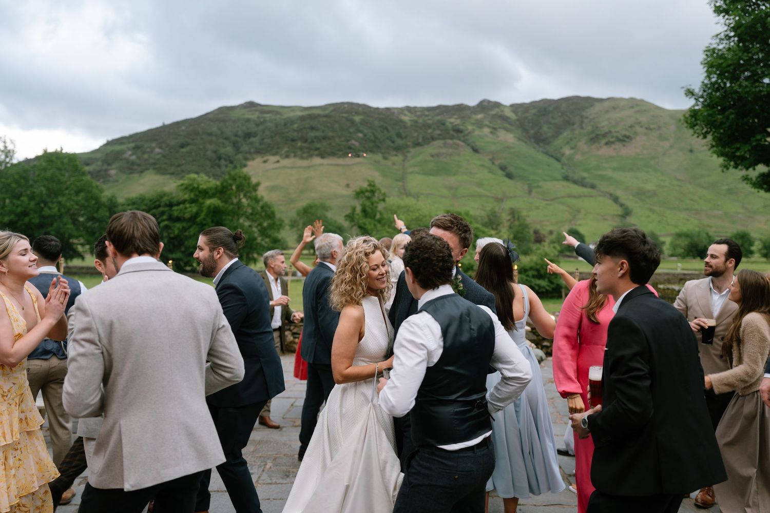 Wedding guests gathered outside with scenic mountain views in background.