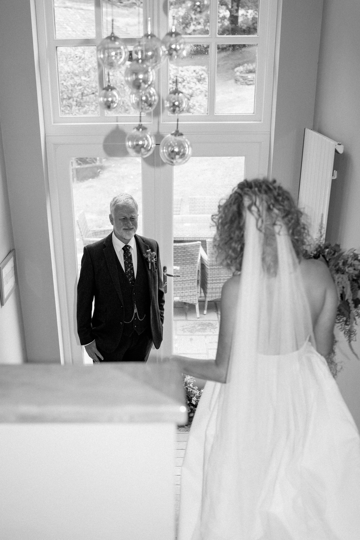 Black and white photos capturing emotional moments before a wedding ceremony in a sunlit room.