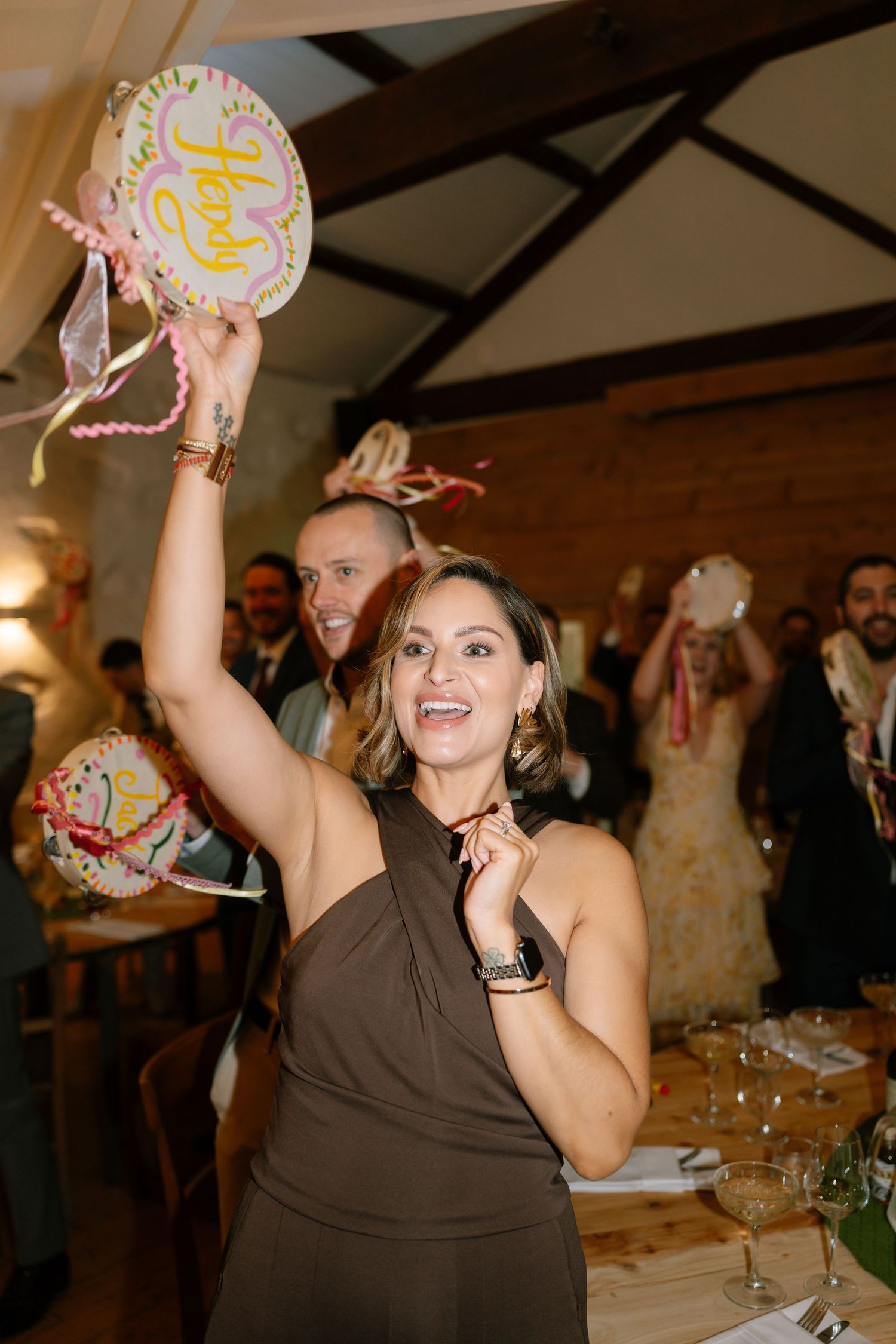A guest in a brown dress dances enthusiastically at a wedding reception.