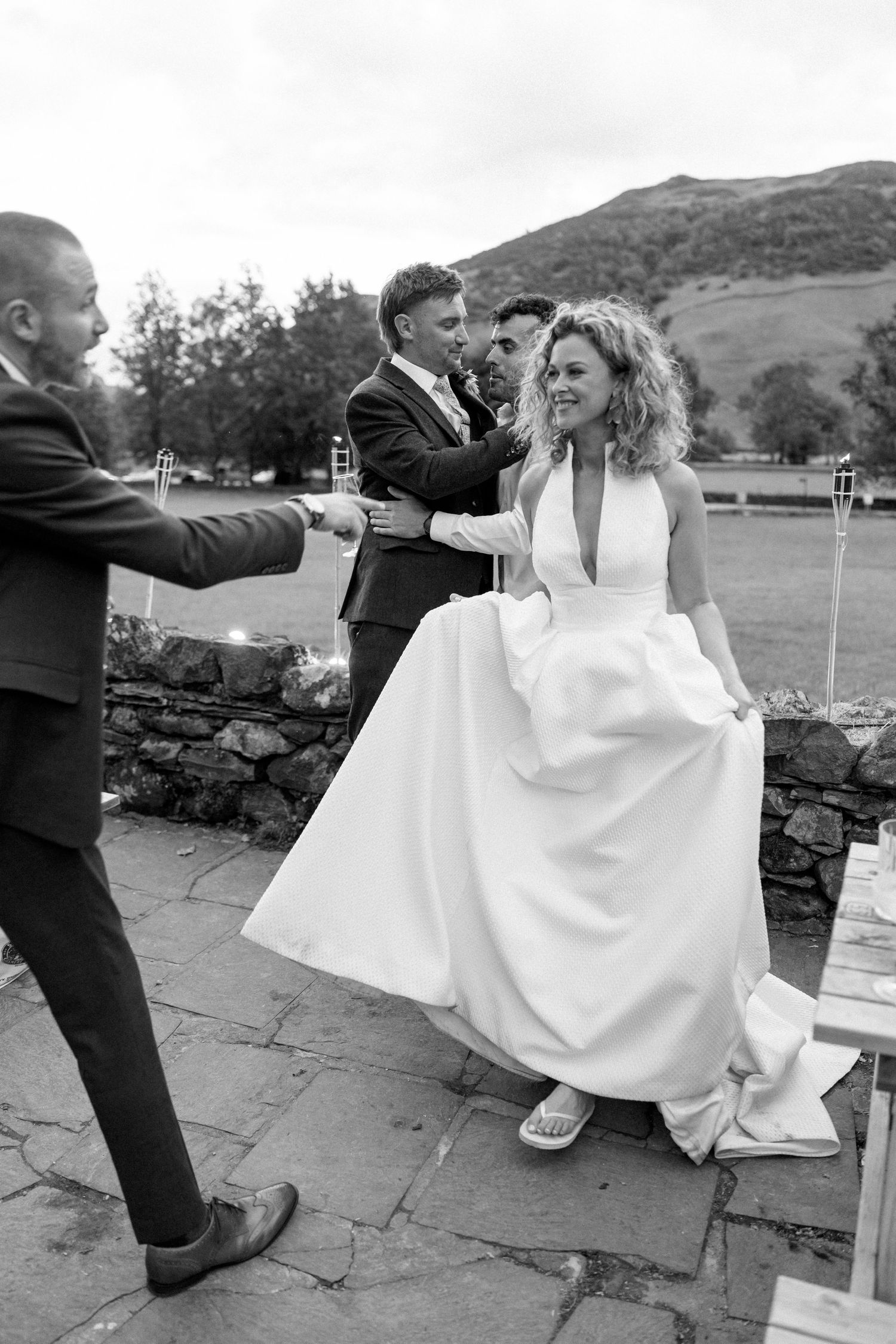 Wedding party relaxes on stone steps during an outdoor celebration.