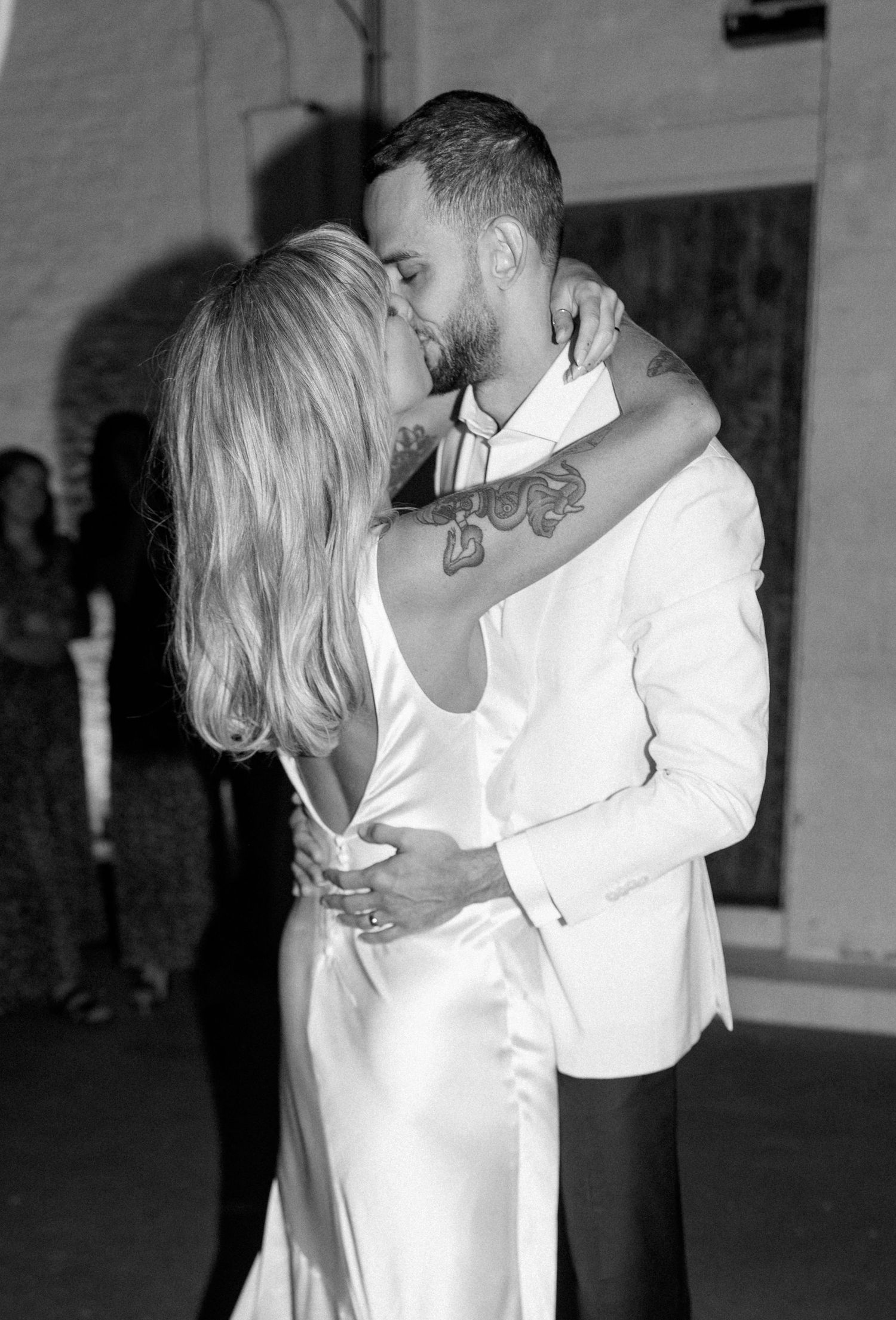 A couple shares an intimate dance moment in black and white at a wedding reception.