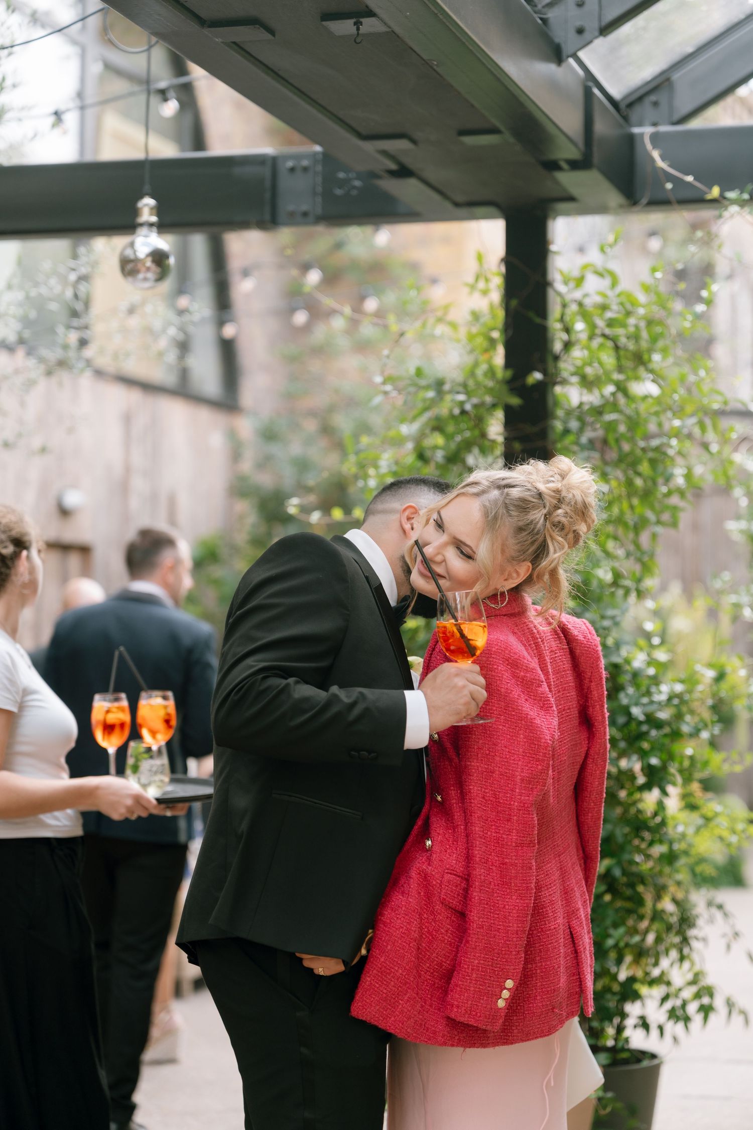 Wedding party members in formal attire celebrate with drinks at an outdoor reception.