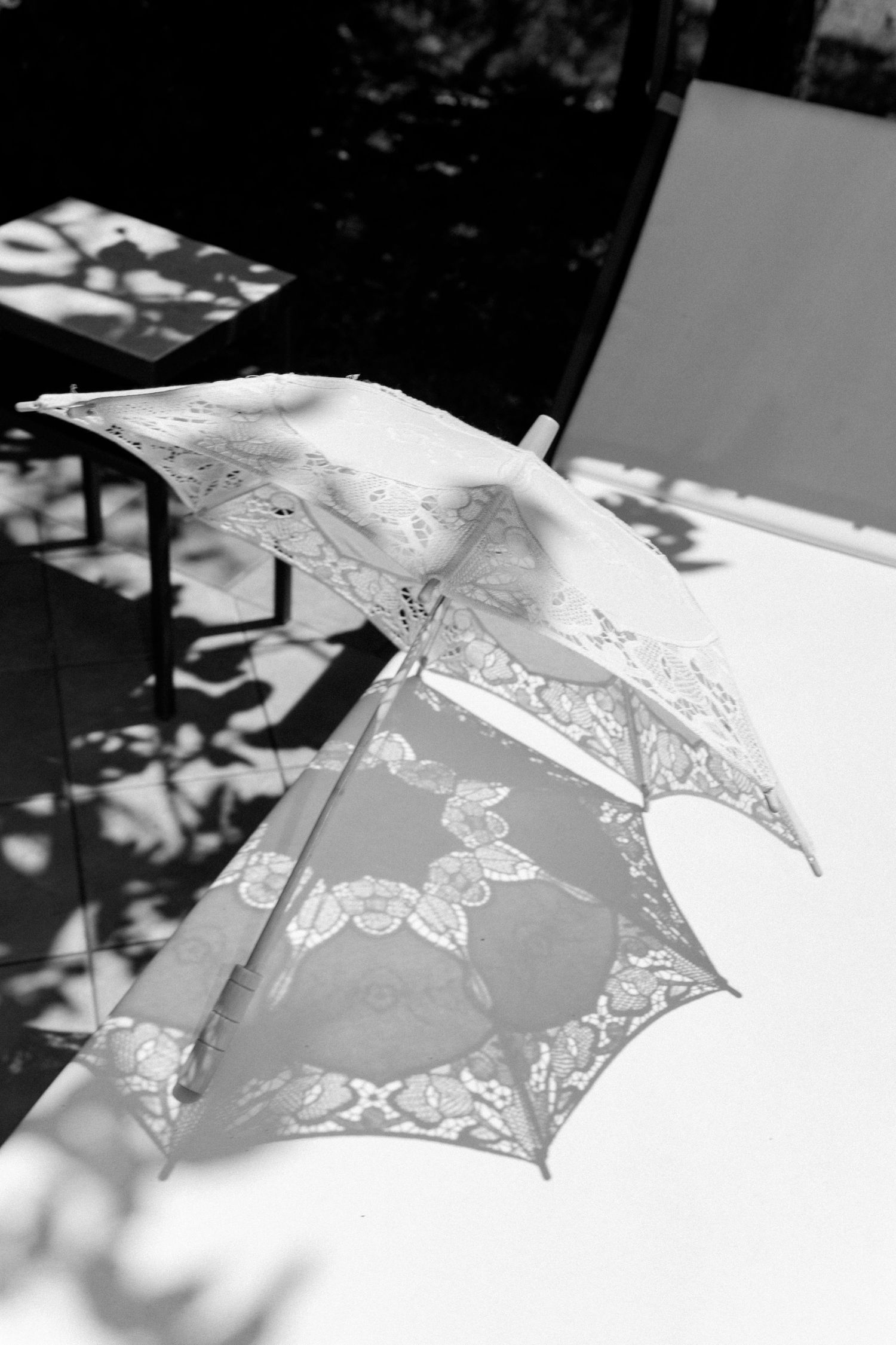 Delicate white lace parasol with butterfly details shown in black and white.