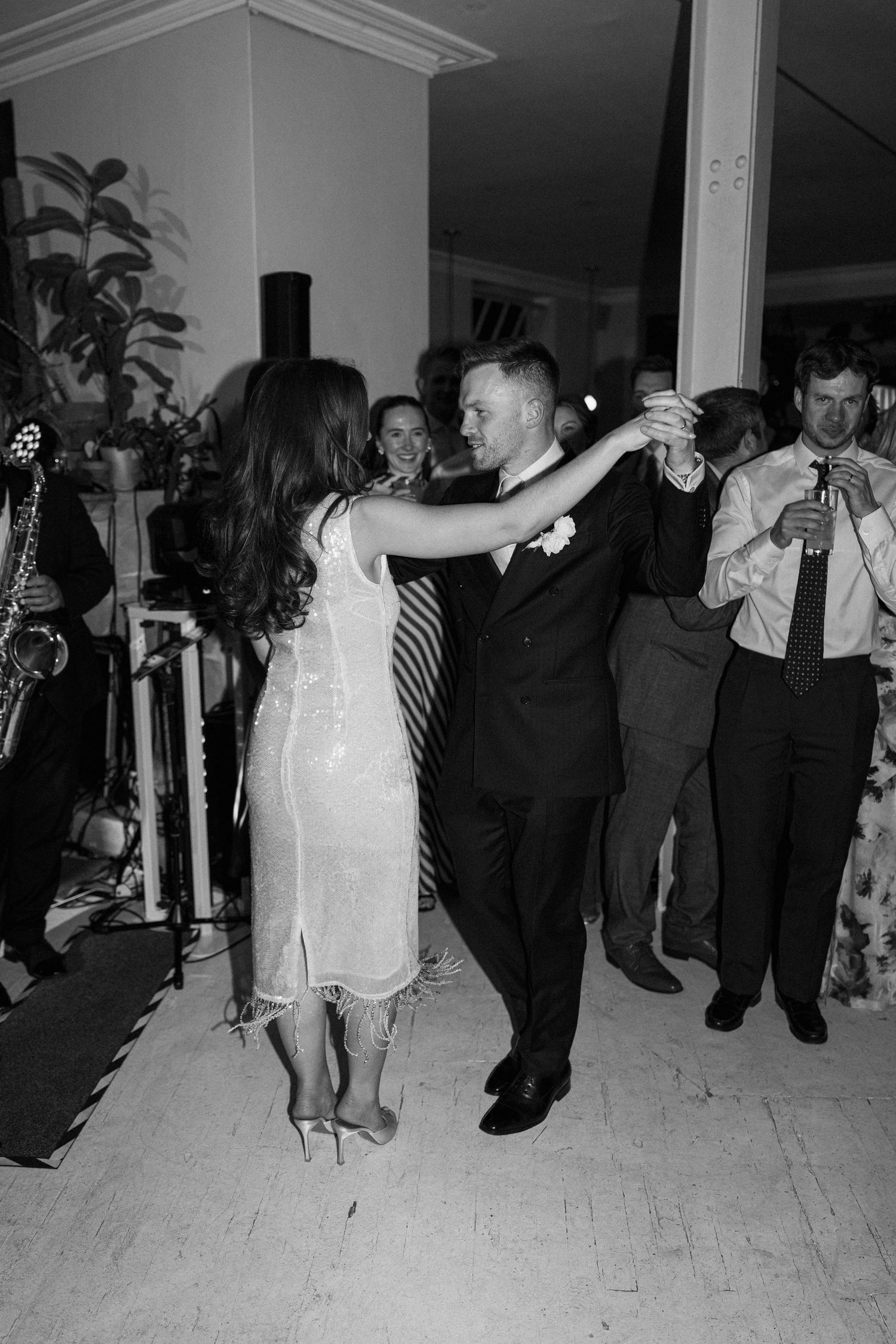 Bride and groom share first dance at wedding reception while live band performs in background.
