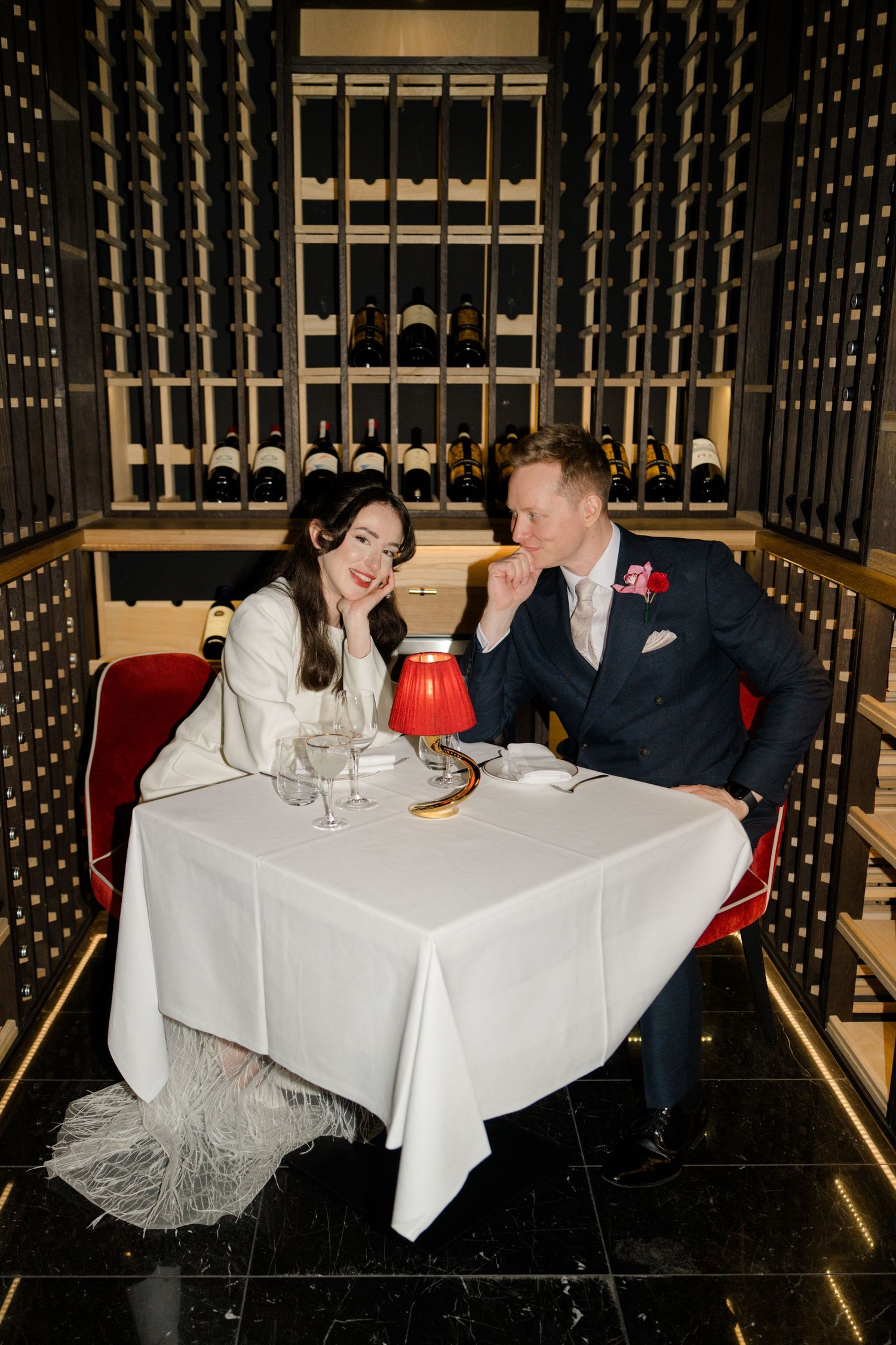 Romantic newlyweds share an intimate moment at a candlelit table surrounded by wine racks in a cellar.