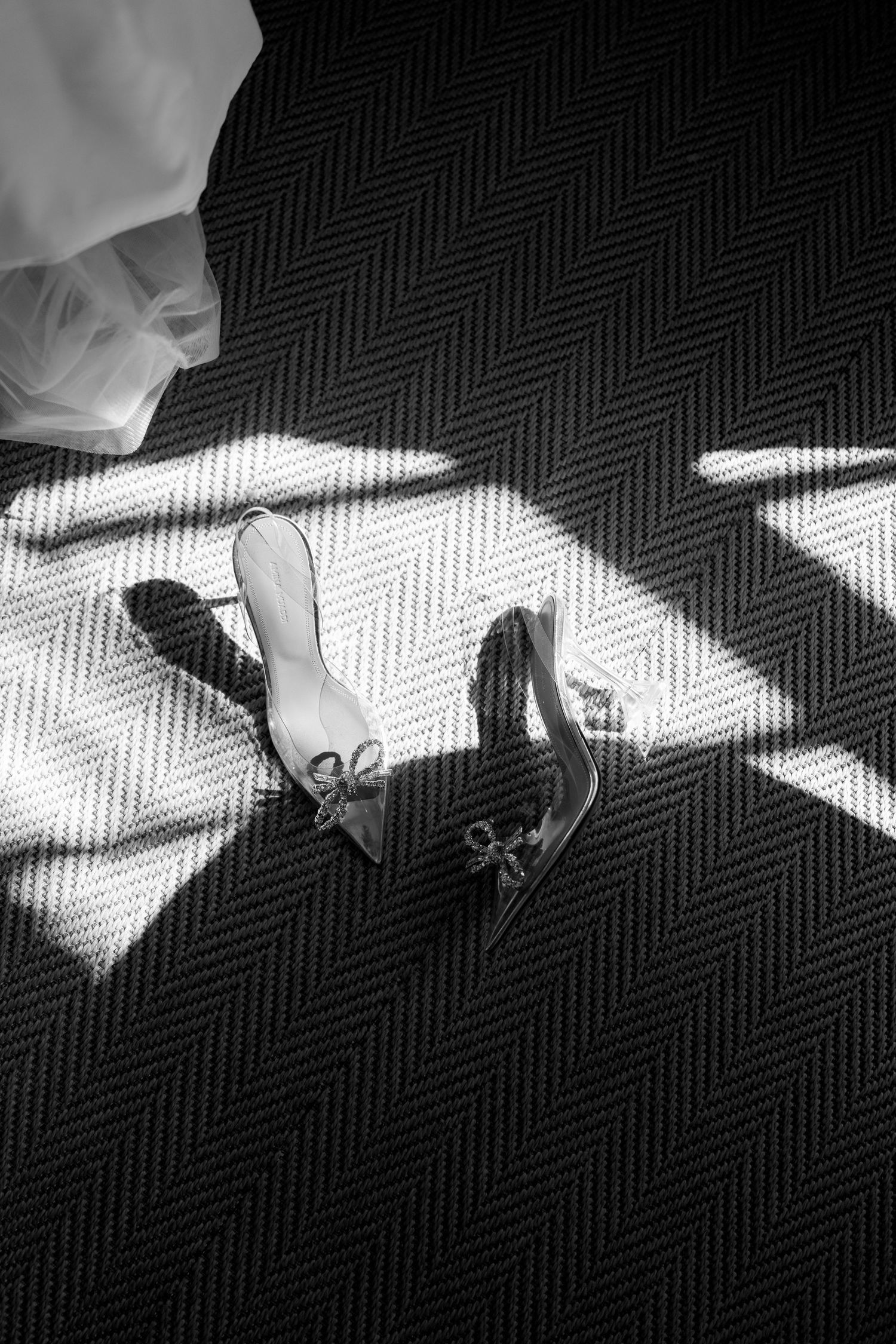 Wedding shoes on herringbone carpet creating dramatic light and shadow patterns.