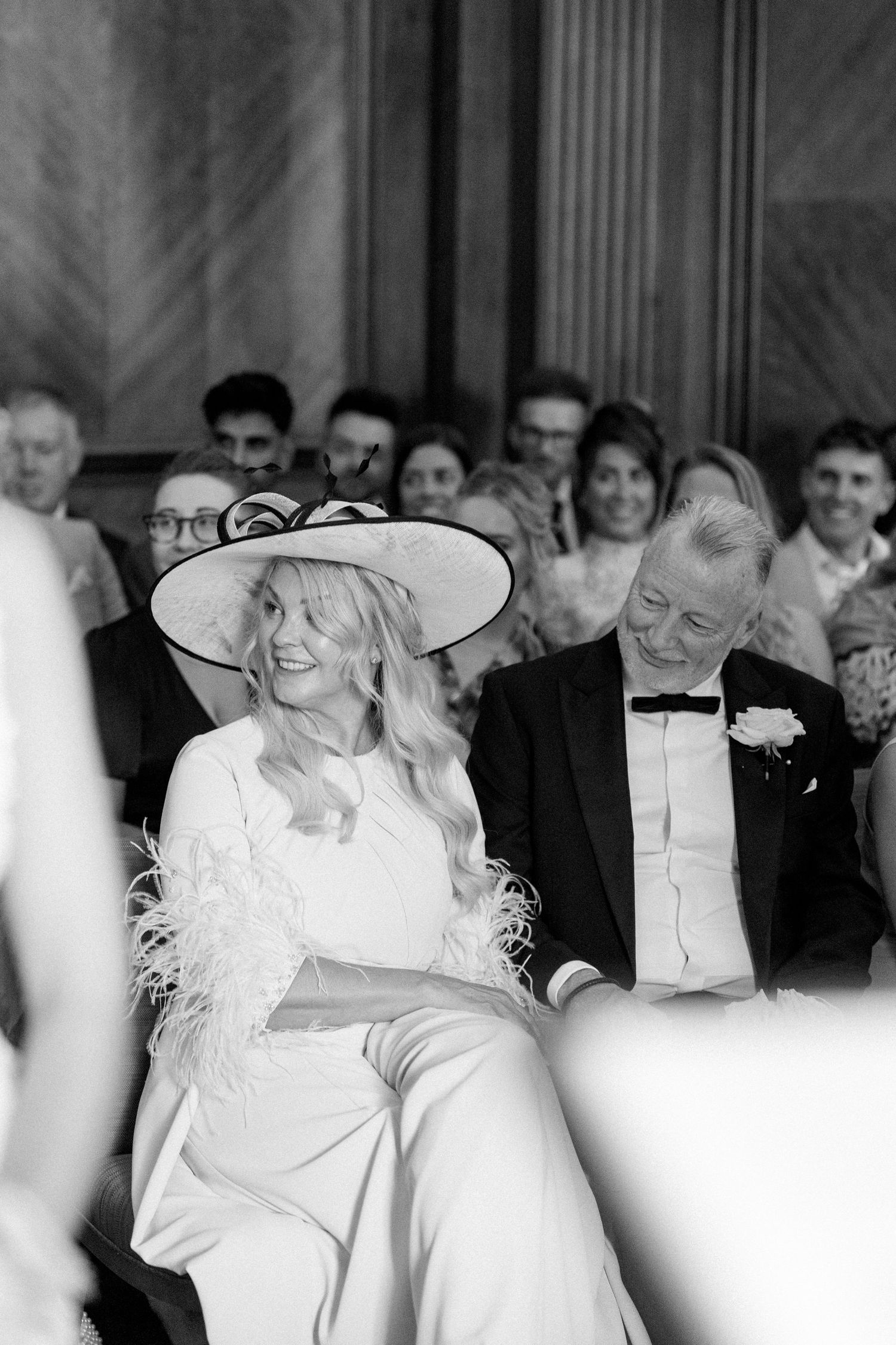 Wedding guests enjoying the celebration in a formal venue with wood paneling.