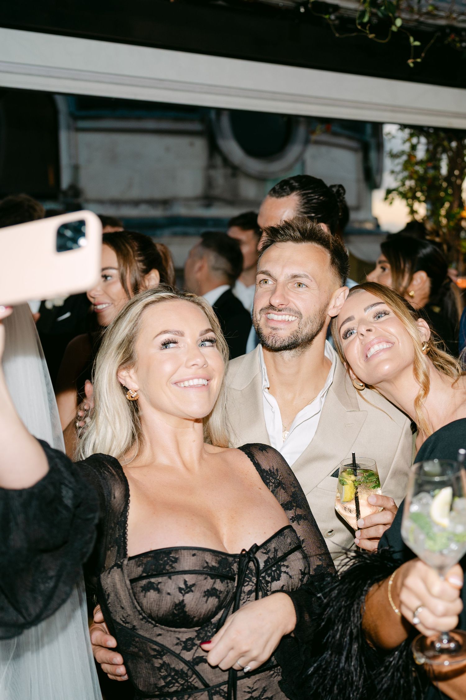 Wedding guests enjoying drinks and laughter during an evening celebration.