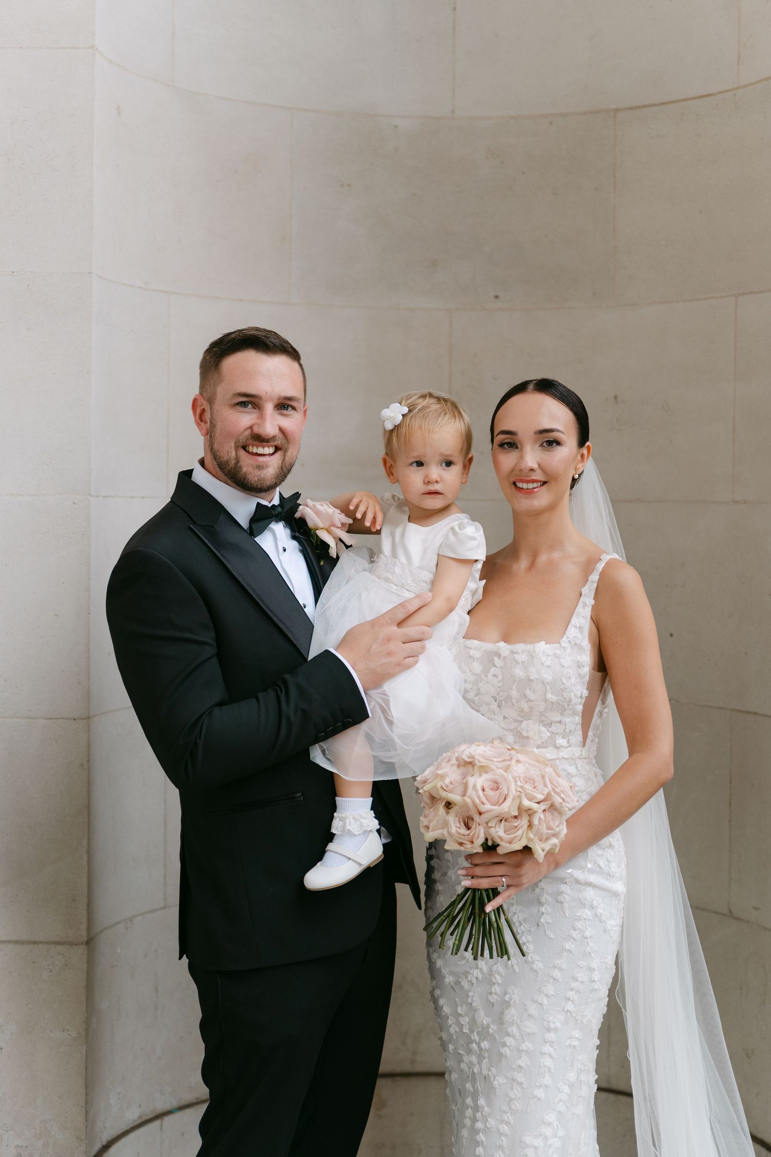 Wedding portrait in front of white stone columns with elegant bridal details.