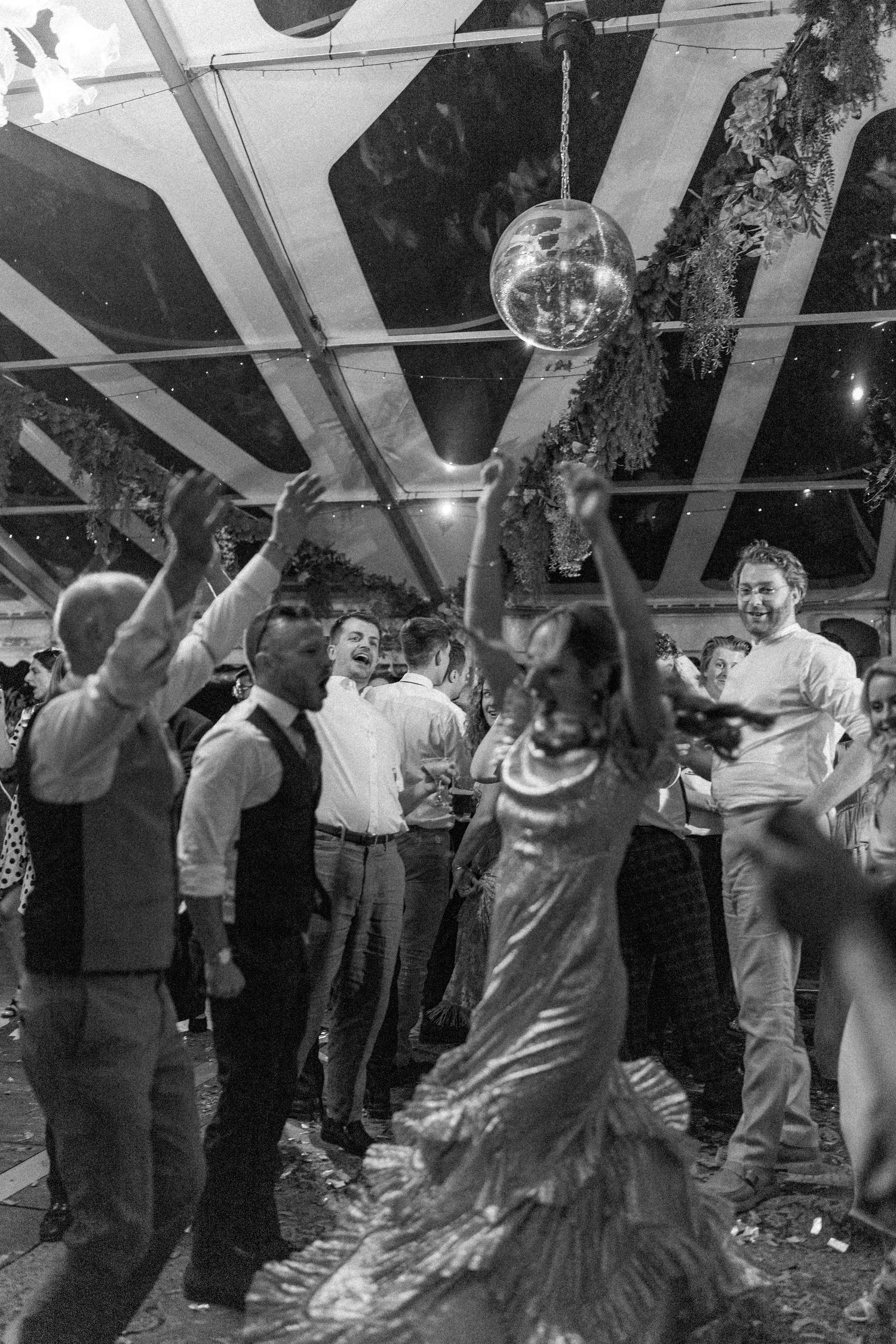 People dancing and celebrating at a lively indoor party with decorative lighting.