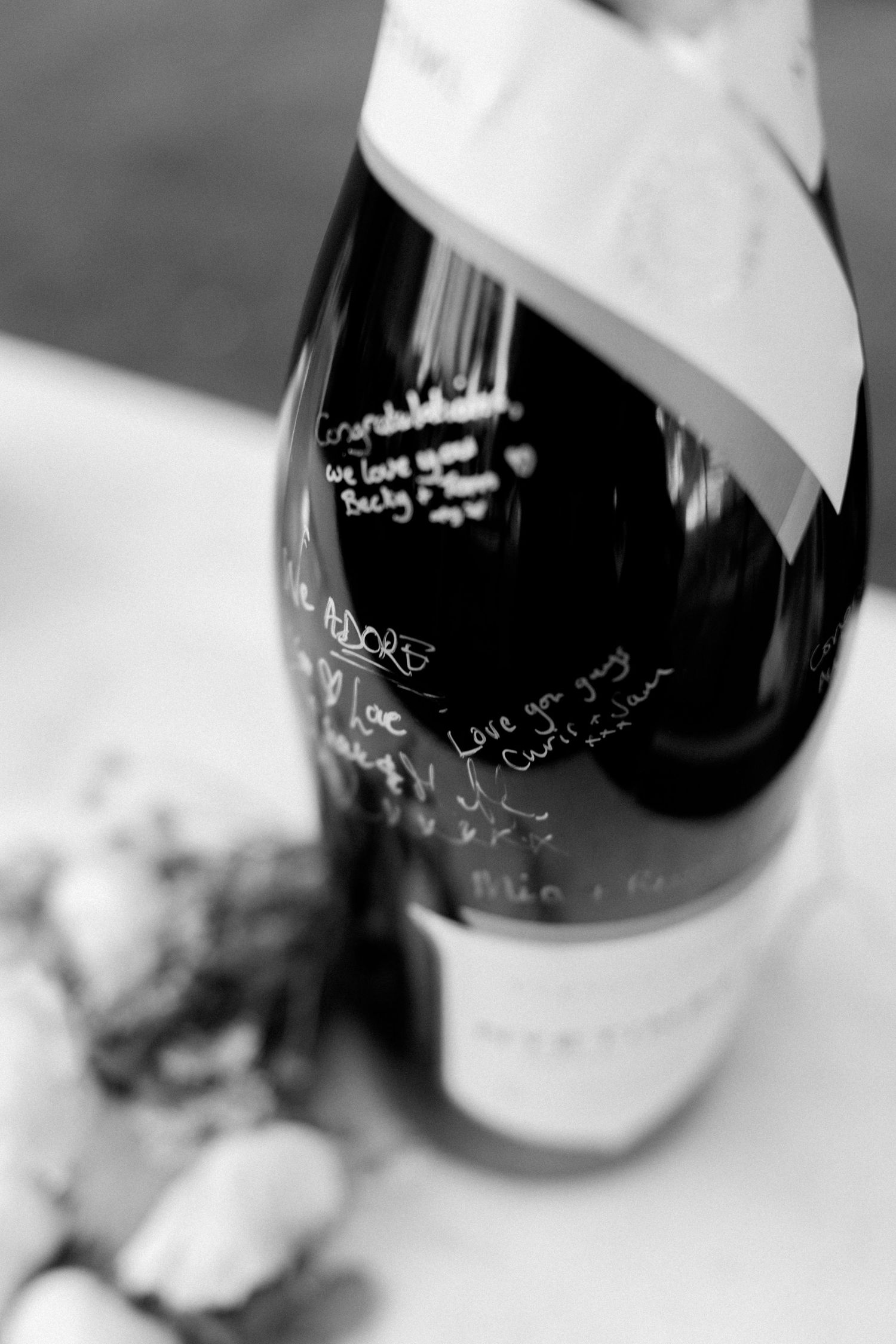 Close-up shots of wine bottles with handwritten signatures in black and white.