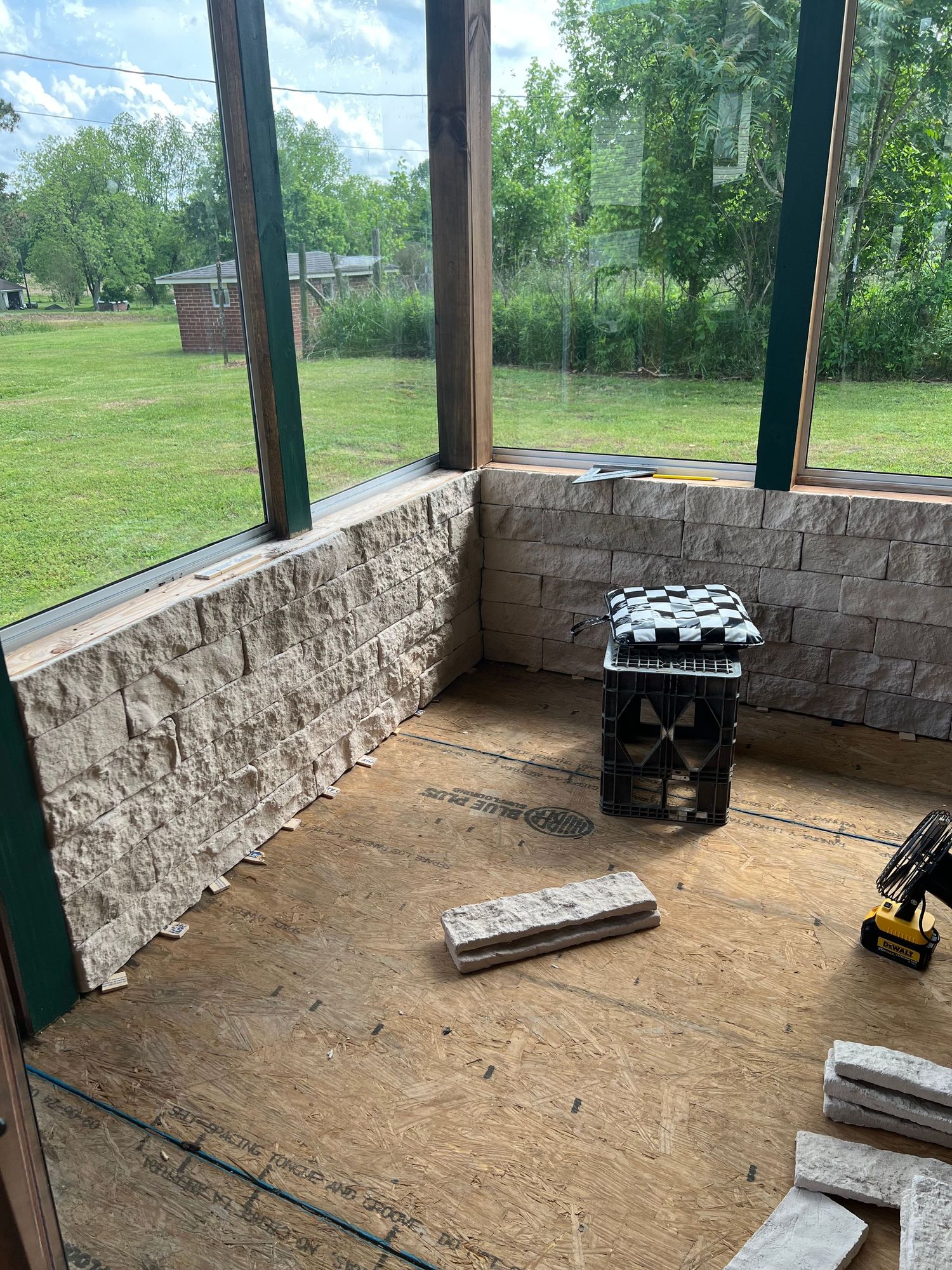 Stone foundation wall with dirt floor under construction showing building materials and tools.