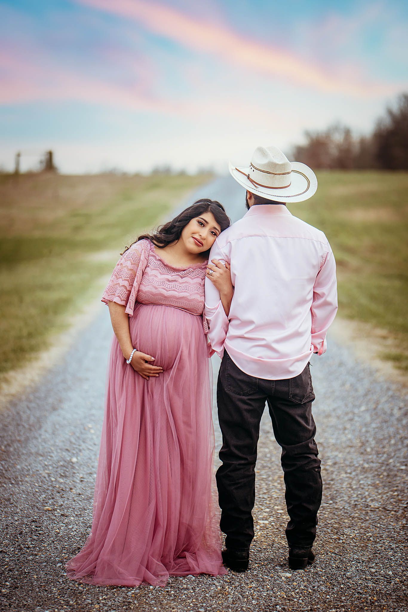 Country-style maternity shoot on a gravel path at dusk.