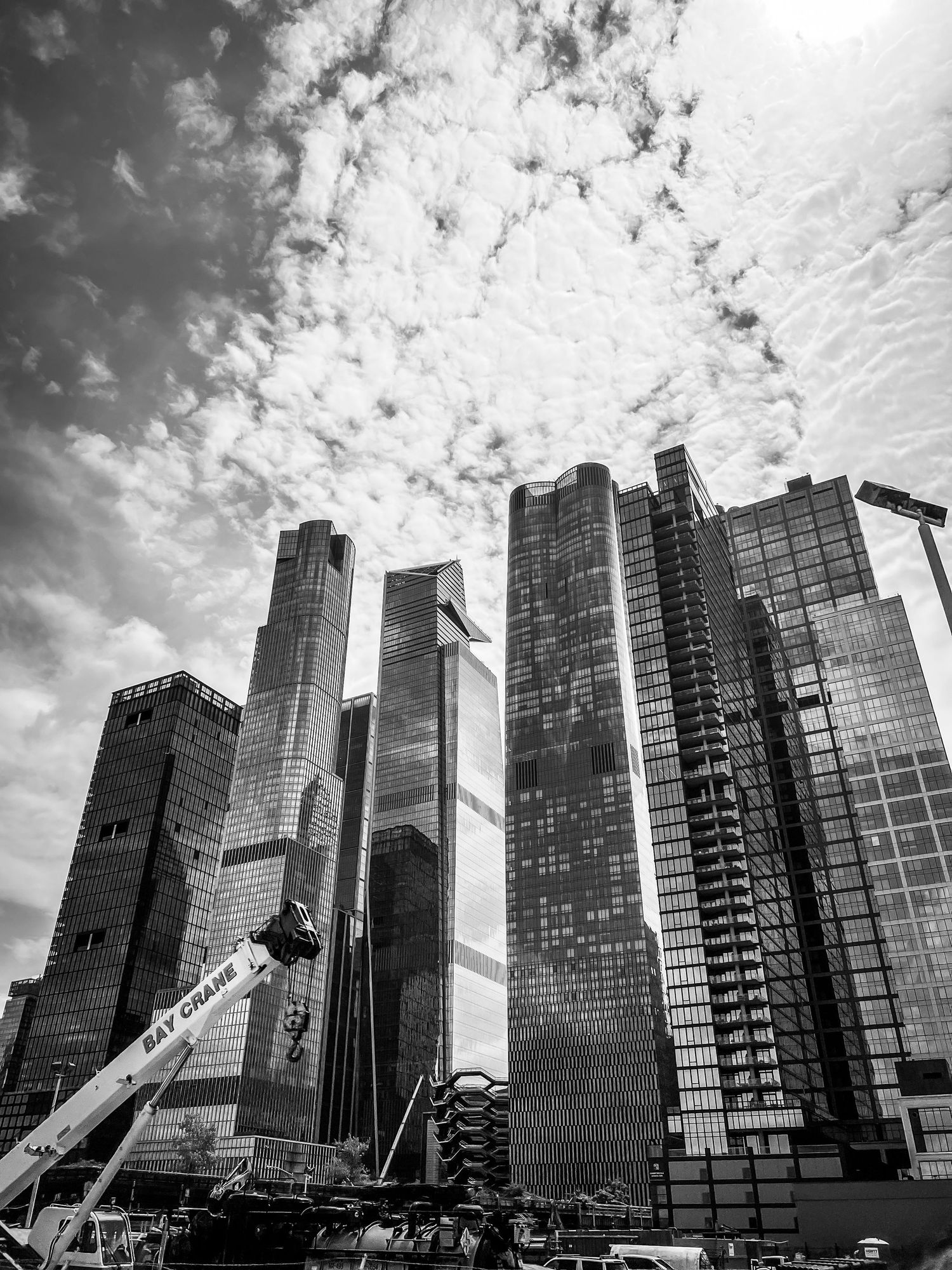 Modern skyscrapers and office buildings stand tall against a dramatic cloudy sky in black and white.