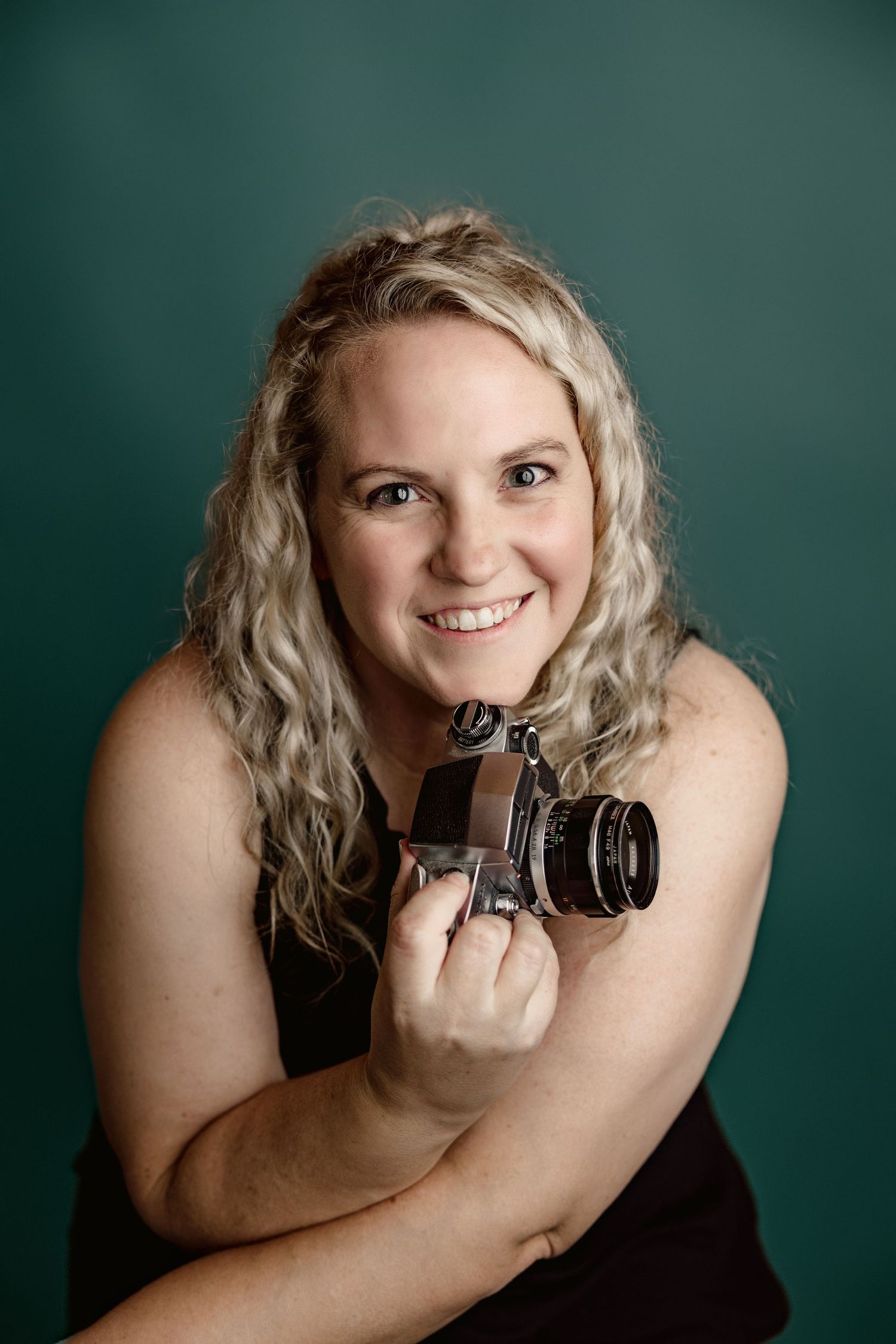 Candid studio shots with a vintage camera against a deep teal background.
