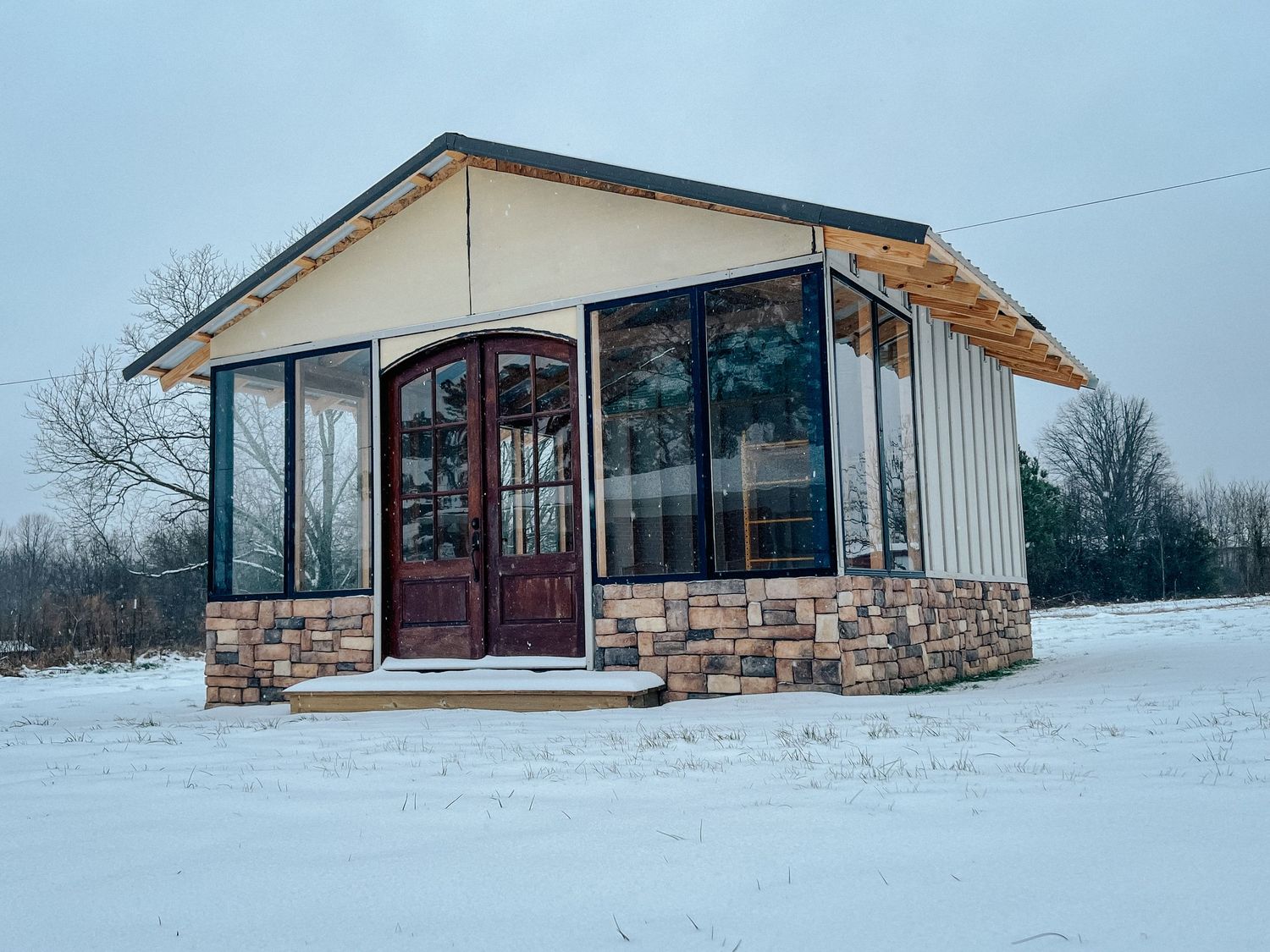 Snow-covered modern ranch house with stone and white siding extends across a winter landscape.