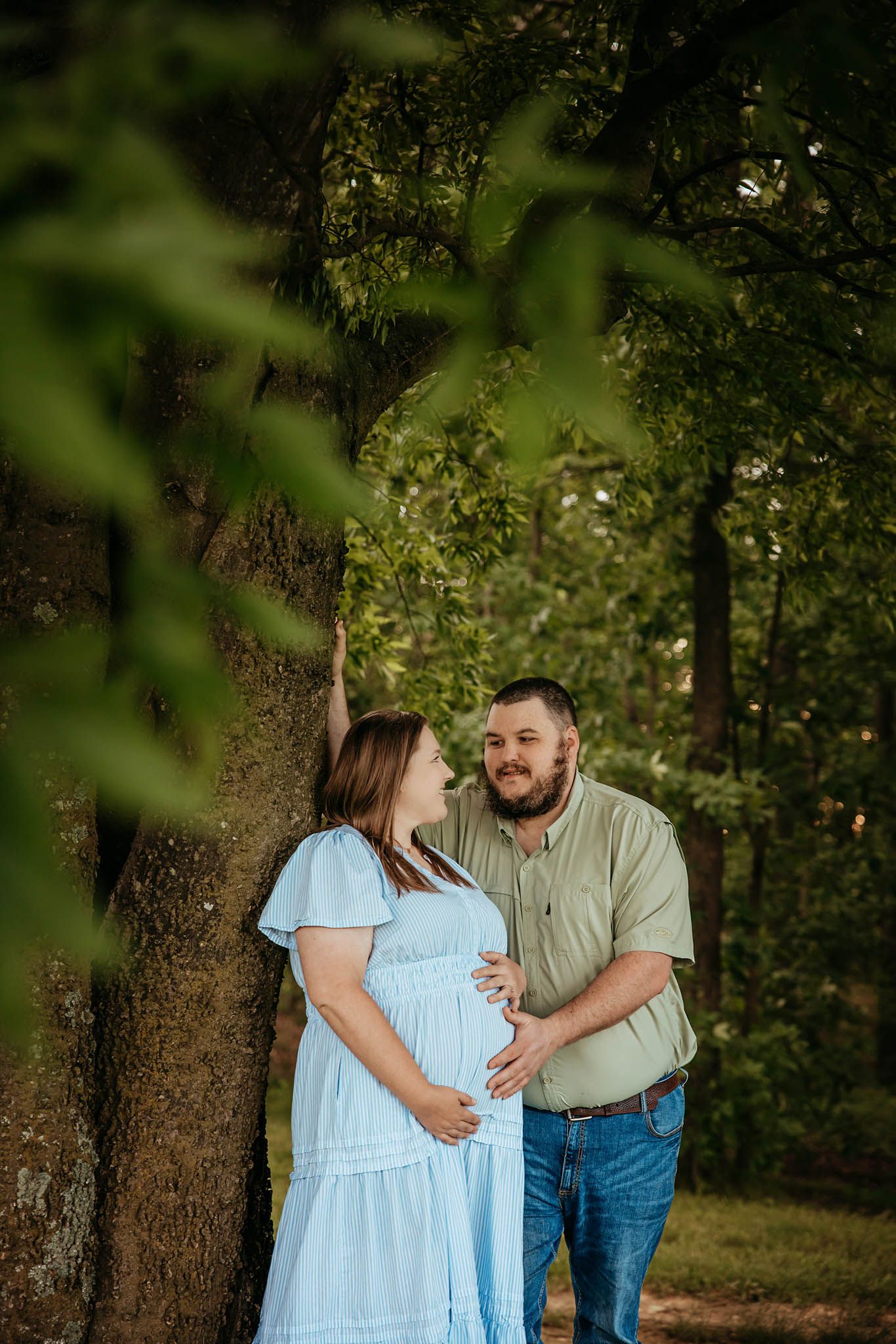 Romantic couple's portrait session in a lush green forest setting.