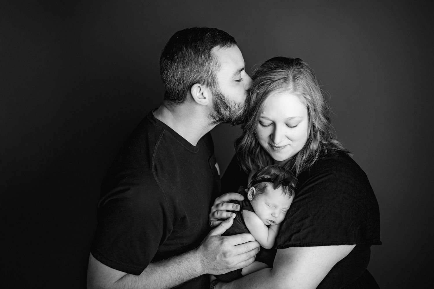 Intimate black and white family portrait in dramatic lighting.