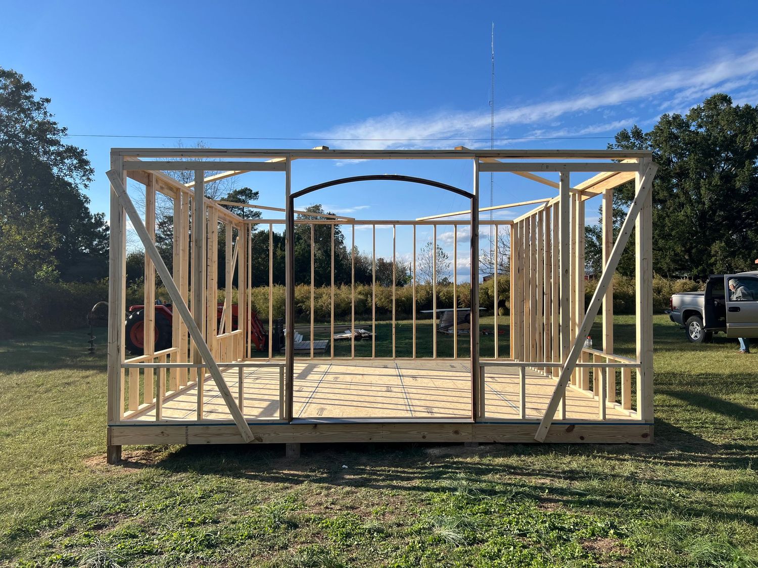 Wooden frame construction showing sequential progress of a small building or shed from foundation to completed structure.