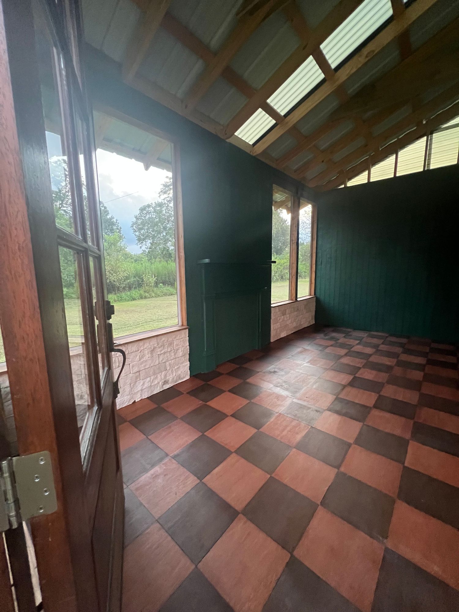 Dark attic interior with angled skylights and geometric red and black checkered floor tiles creating visual interest.