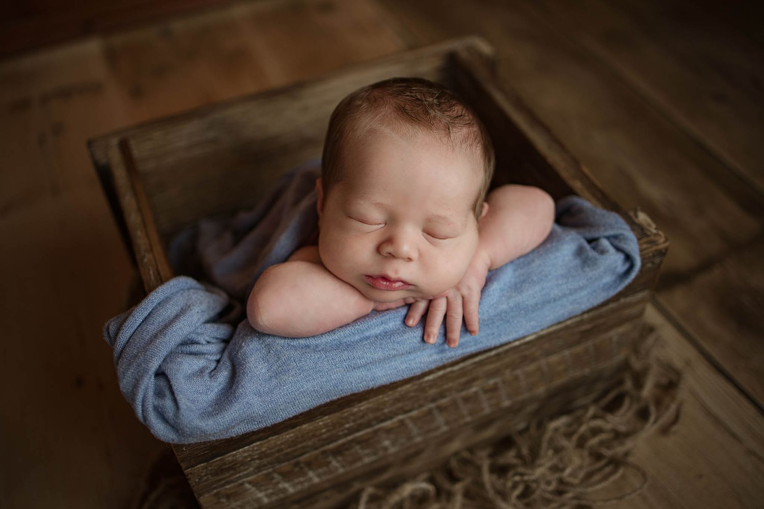 Peaceful sleeping baby on blue fabric in vintage wooden box.