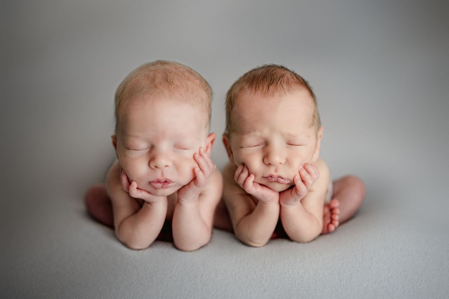 Artistic portrait of sleeping newborn twins in minimalist style.
