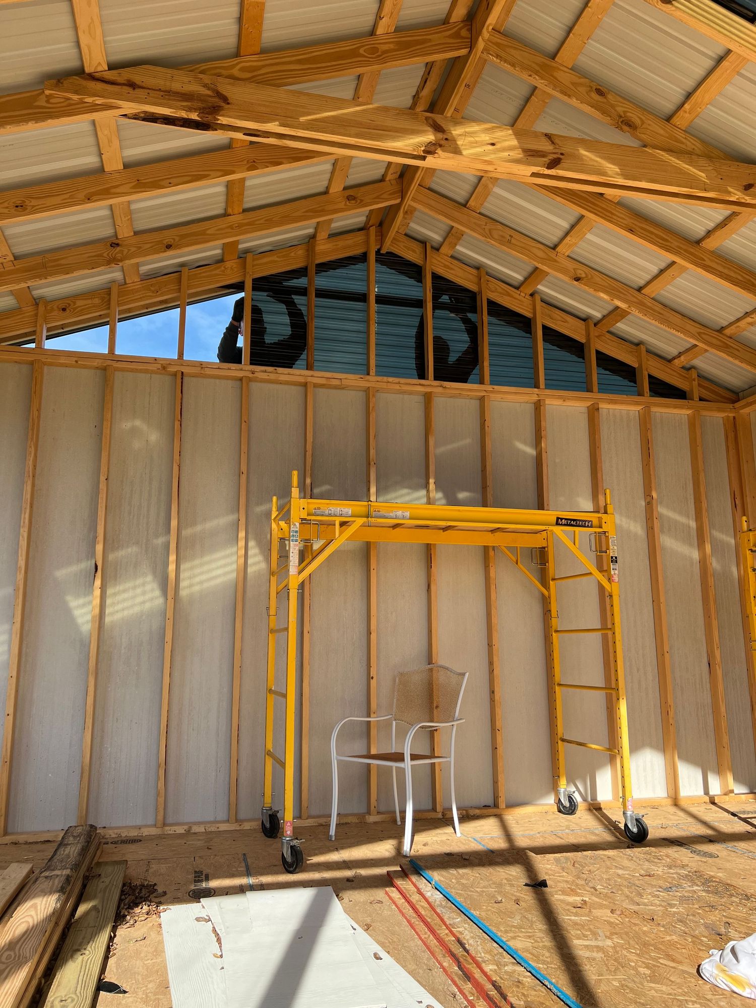 Interior of an unfinished wooden garage or workshop showing exposed framing and yellow support beams.