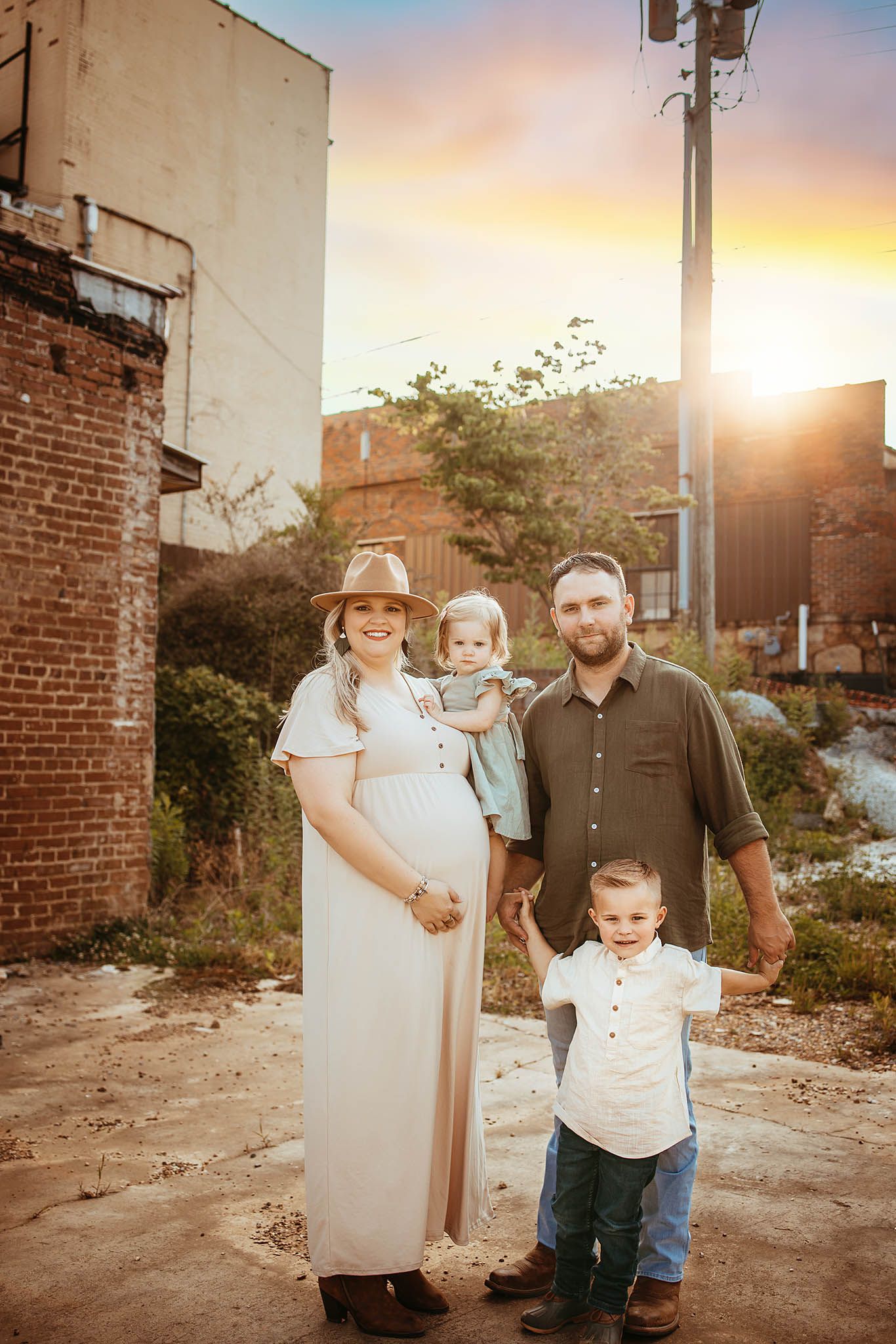 Family portrait at sunset against brick wall and urban backdrop.