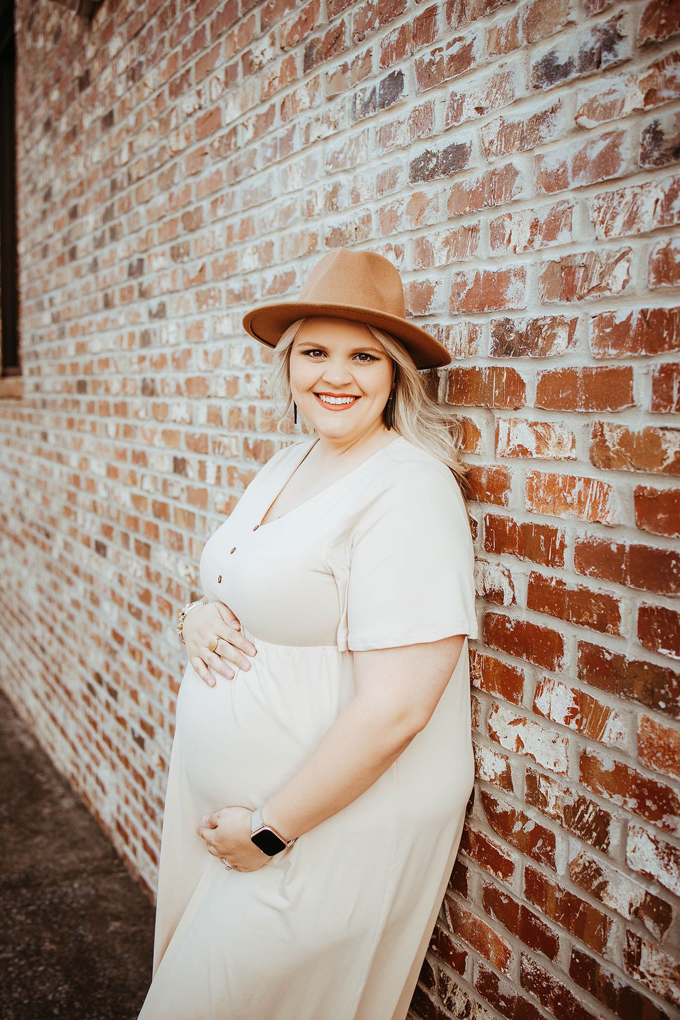 Maternity photo series against brick wall showing someone in white dress and tan hat from various angles.