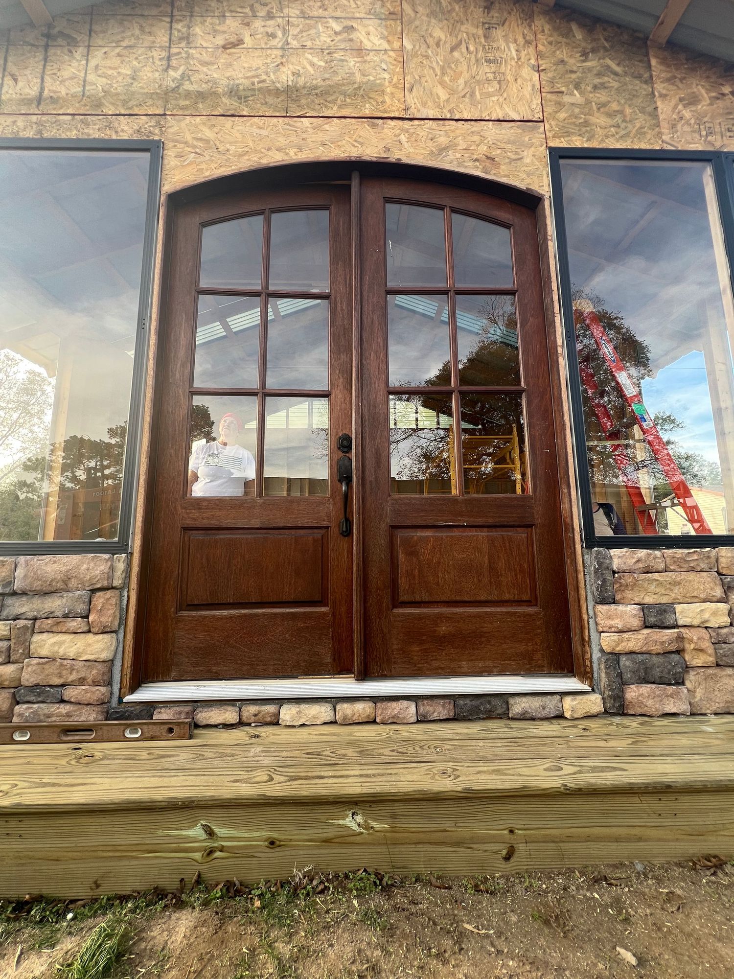 Rustic wood and stone building facade with windows and overhanging deck at twilight.