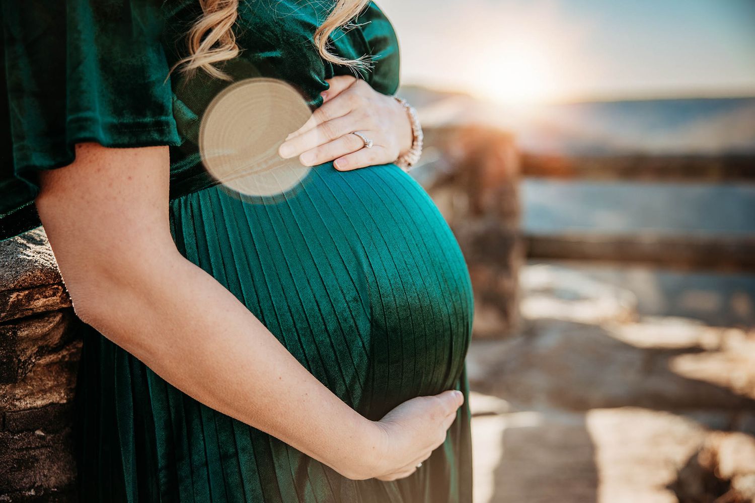 Intimate maternity photos captured against a seaside sunset backdrop.
