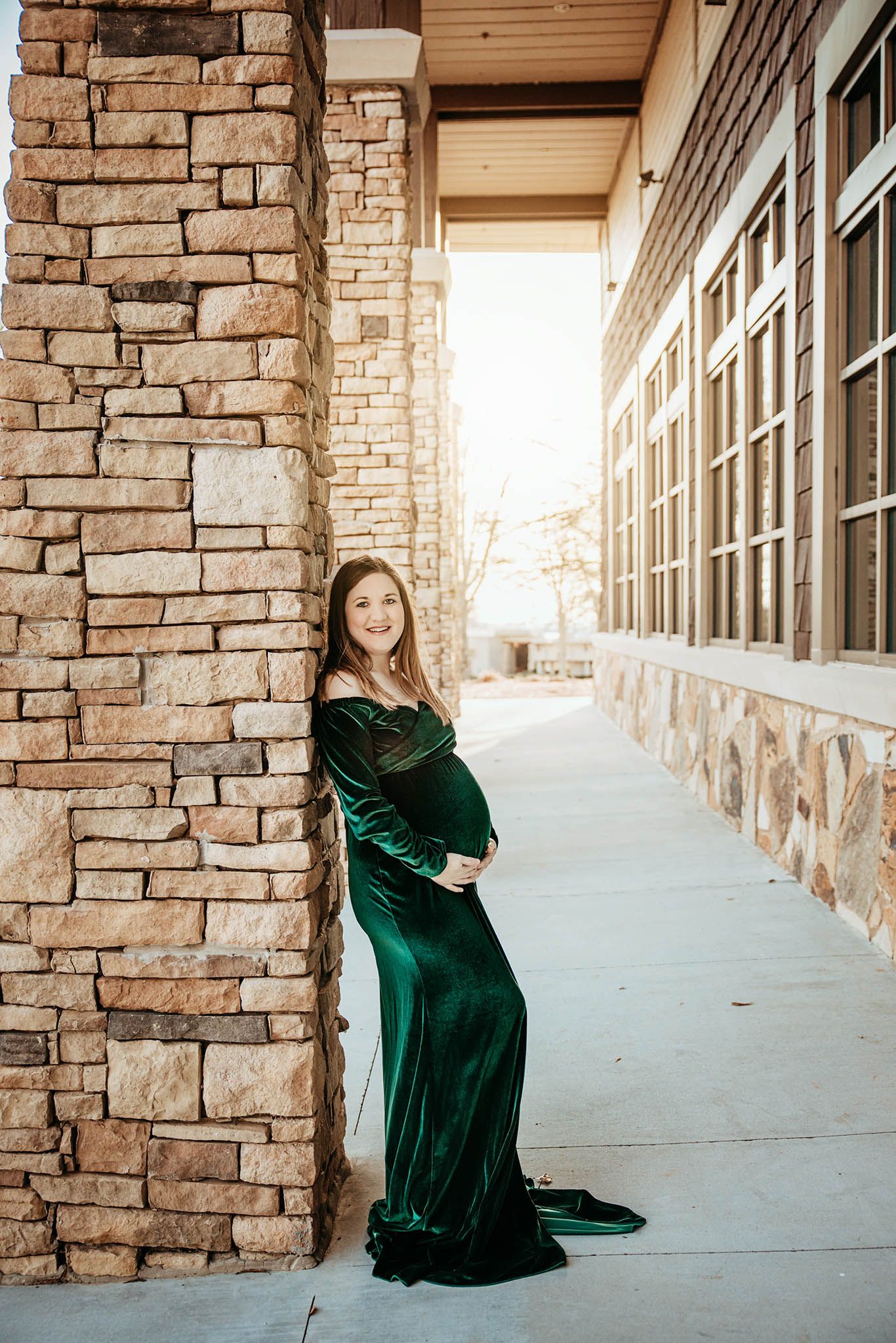 A series of three portrait shots showcasing an emerald green velvet dress against a stone and brick exterior hallway.