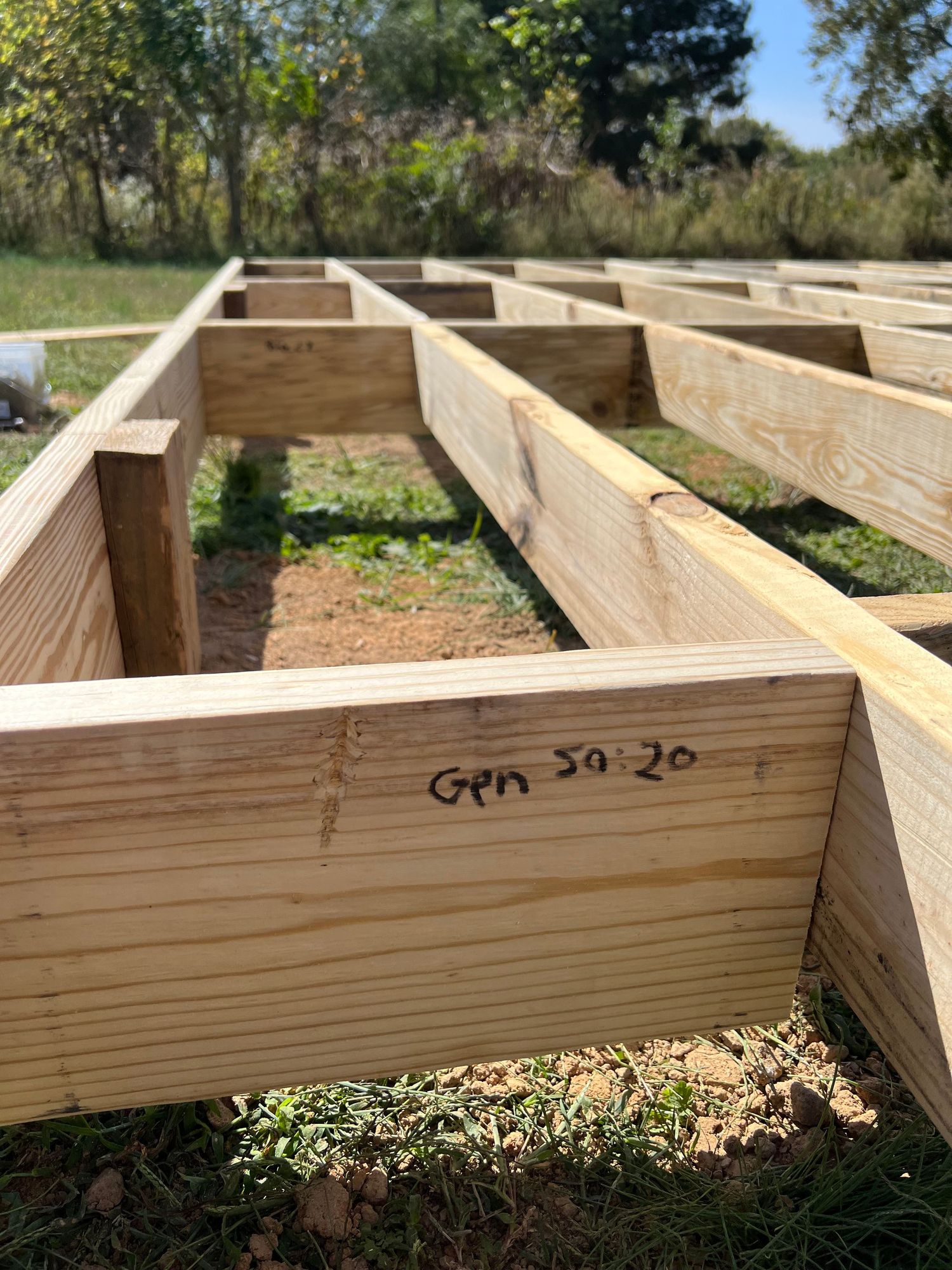 Close-up view of wooden boards being assembled into what appears to be floor joists for outdoor construction.