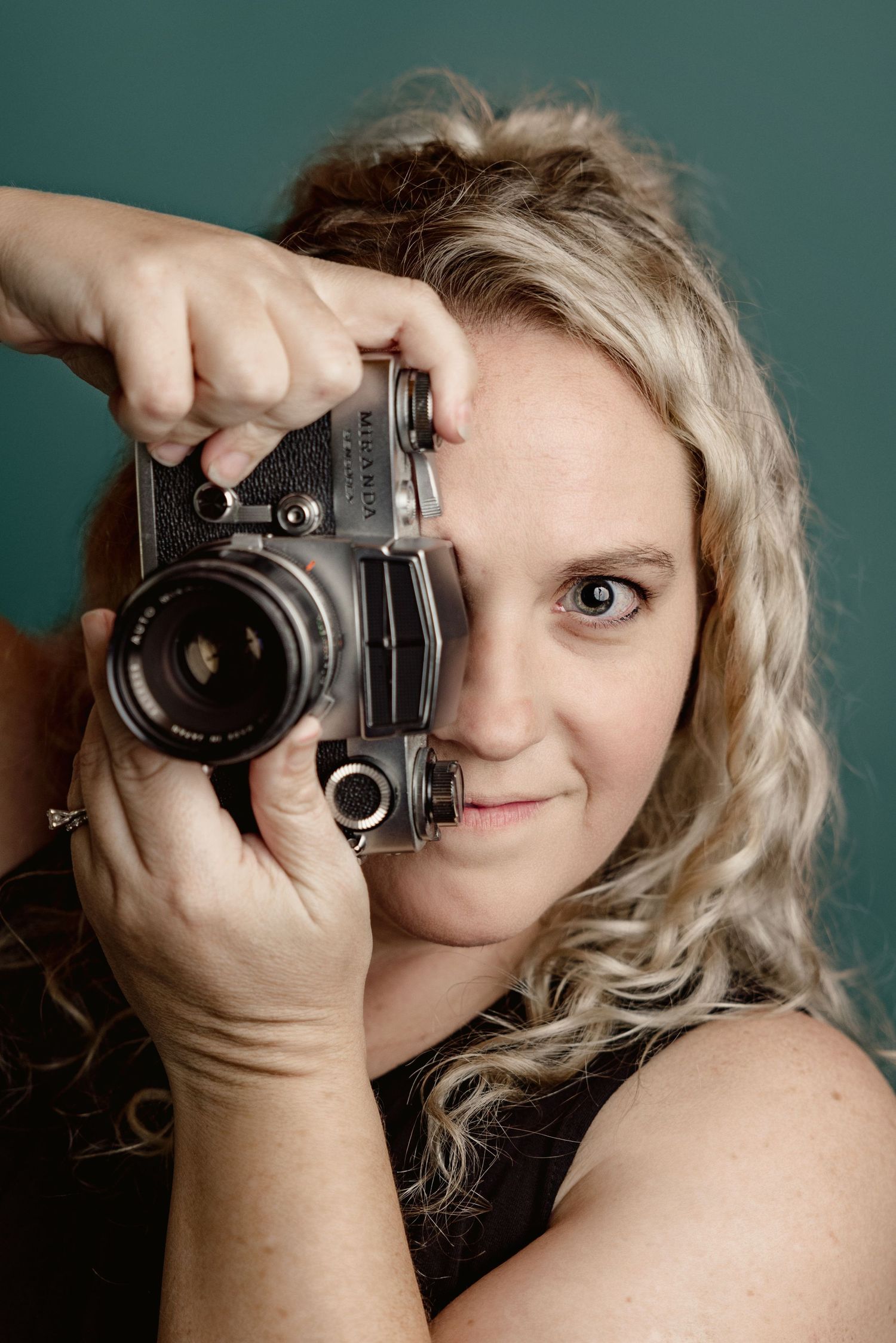 Creative self-portraits with a vintage camera against teal studio backdrop.