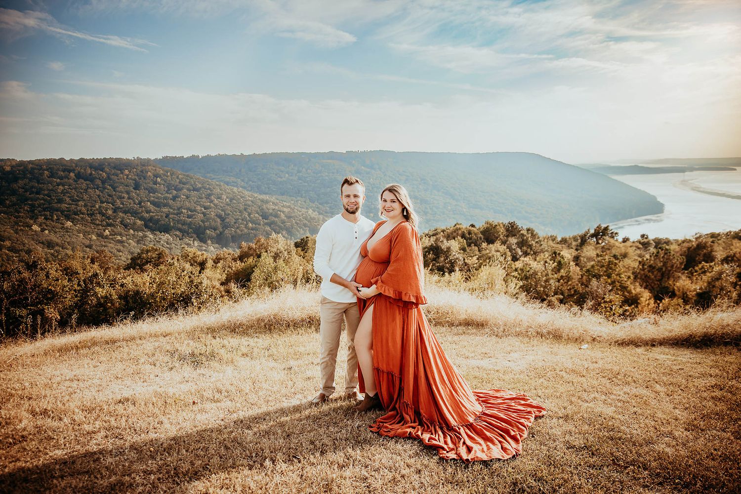 Scenic mountain landscape at sunset with a coral dress flowing in the golden light.