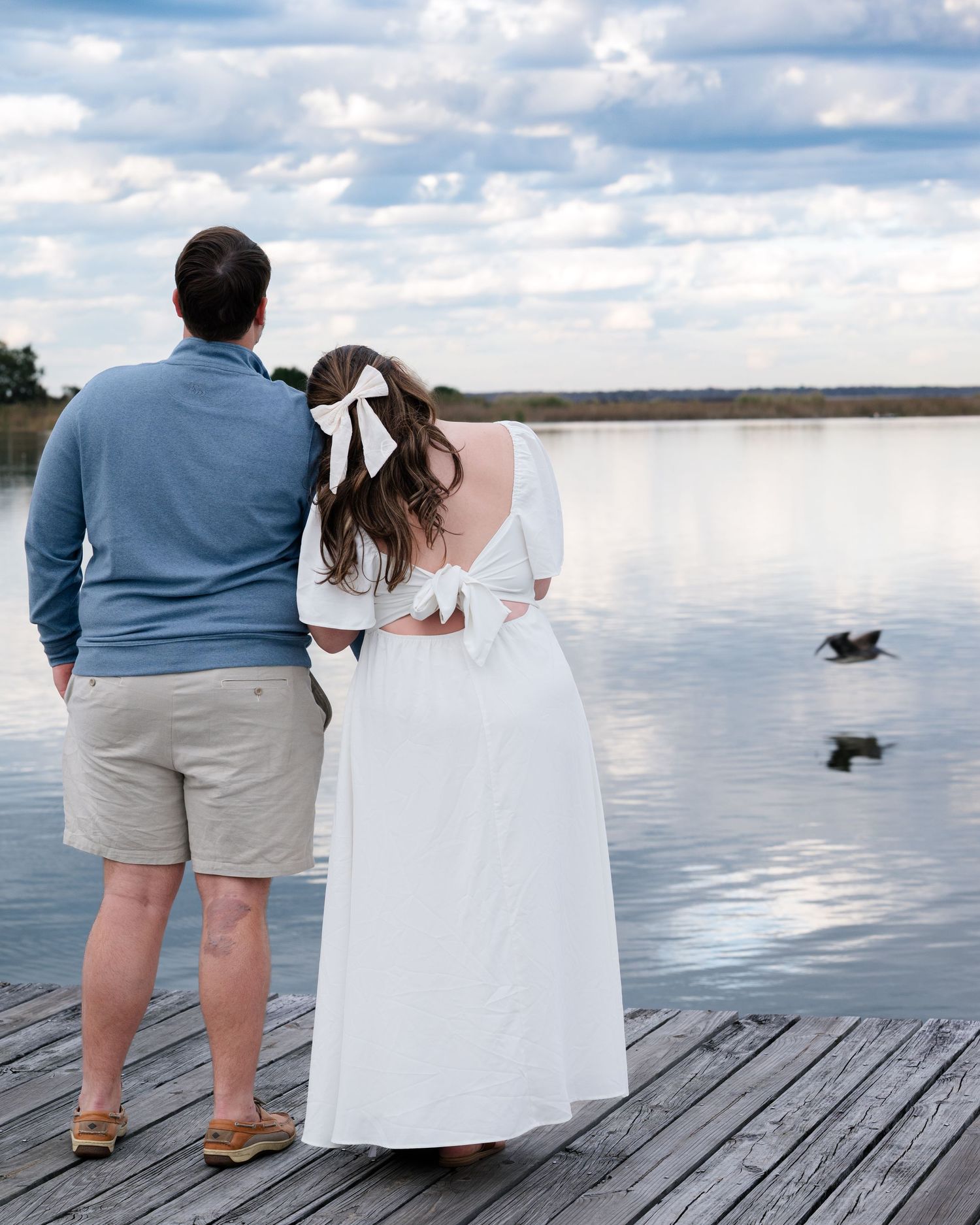 A couple standing on a wooden dock overlooking a peaceful river.