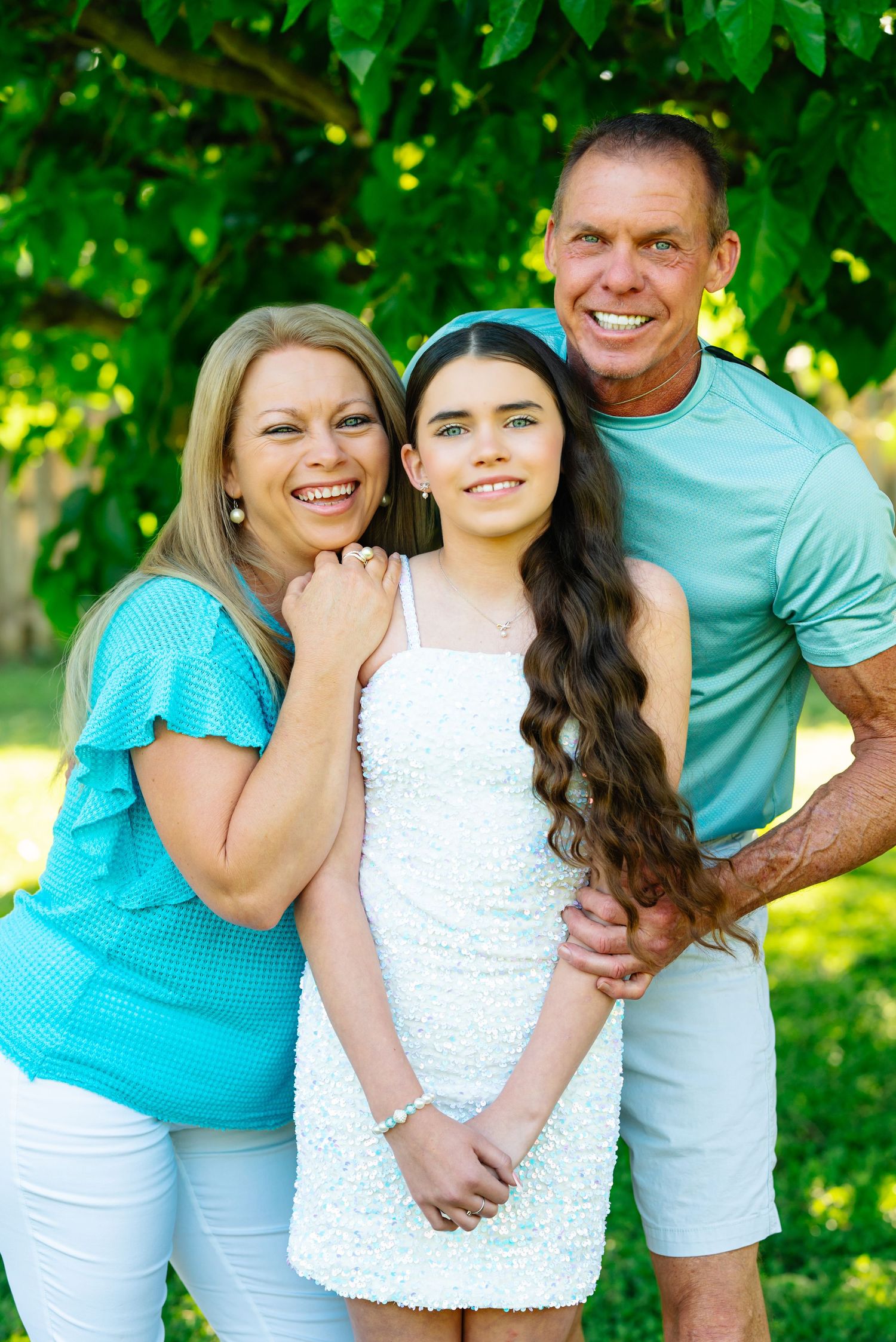 Family photo sequence in bright summer outfits with turquoise and white clothing against green foliage.