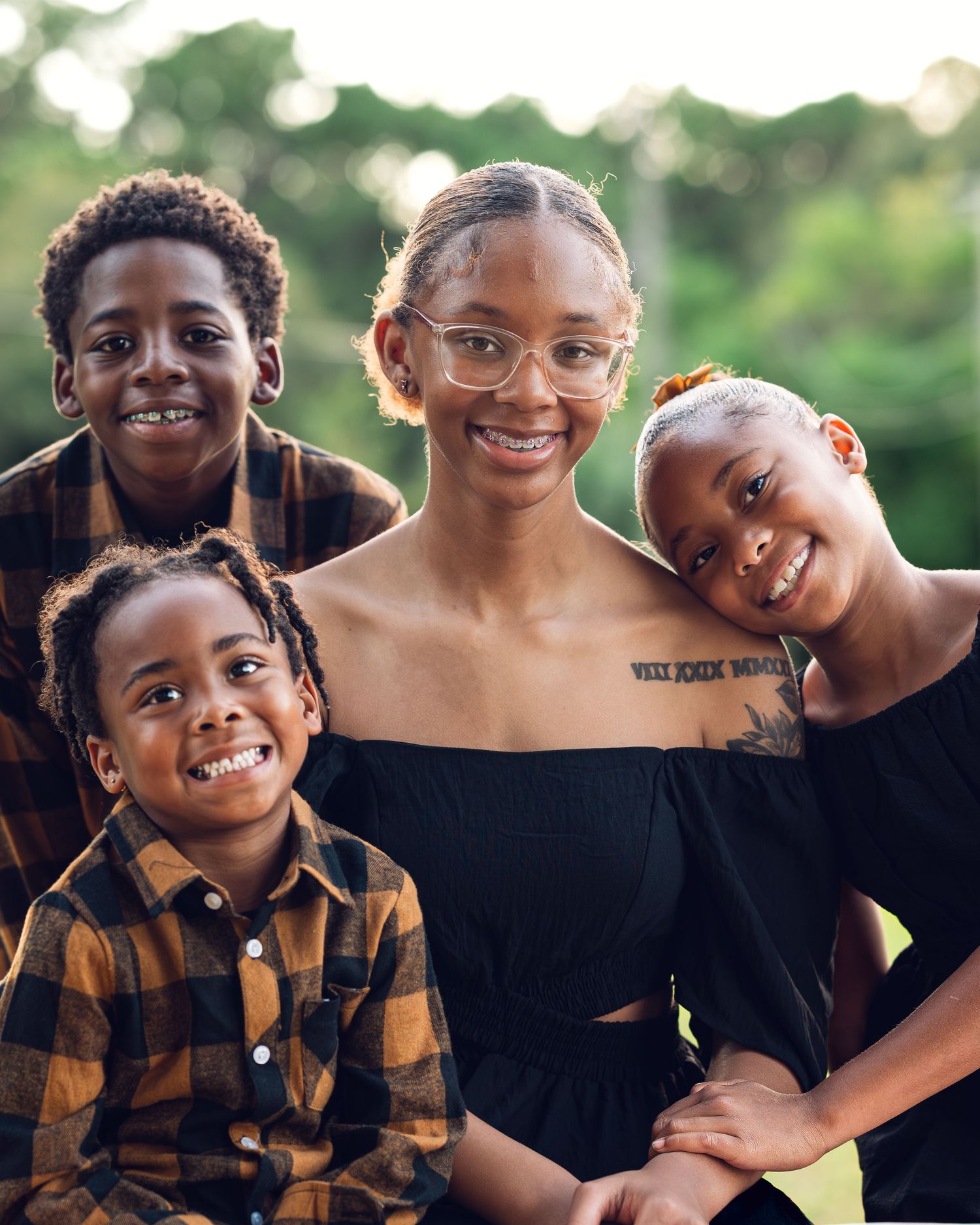 Family group wearing casual clothing poses together outdoors during golden hour.