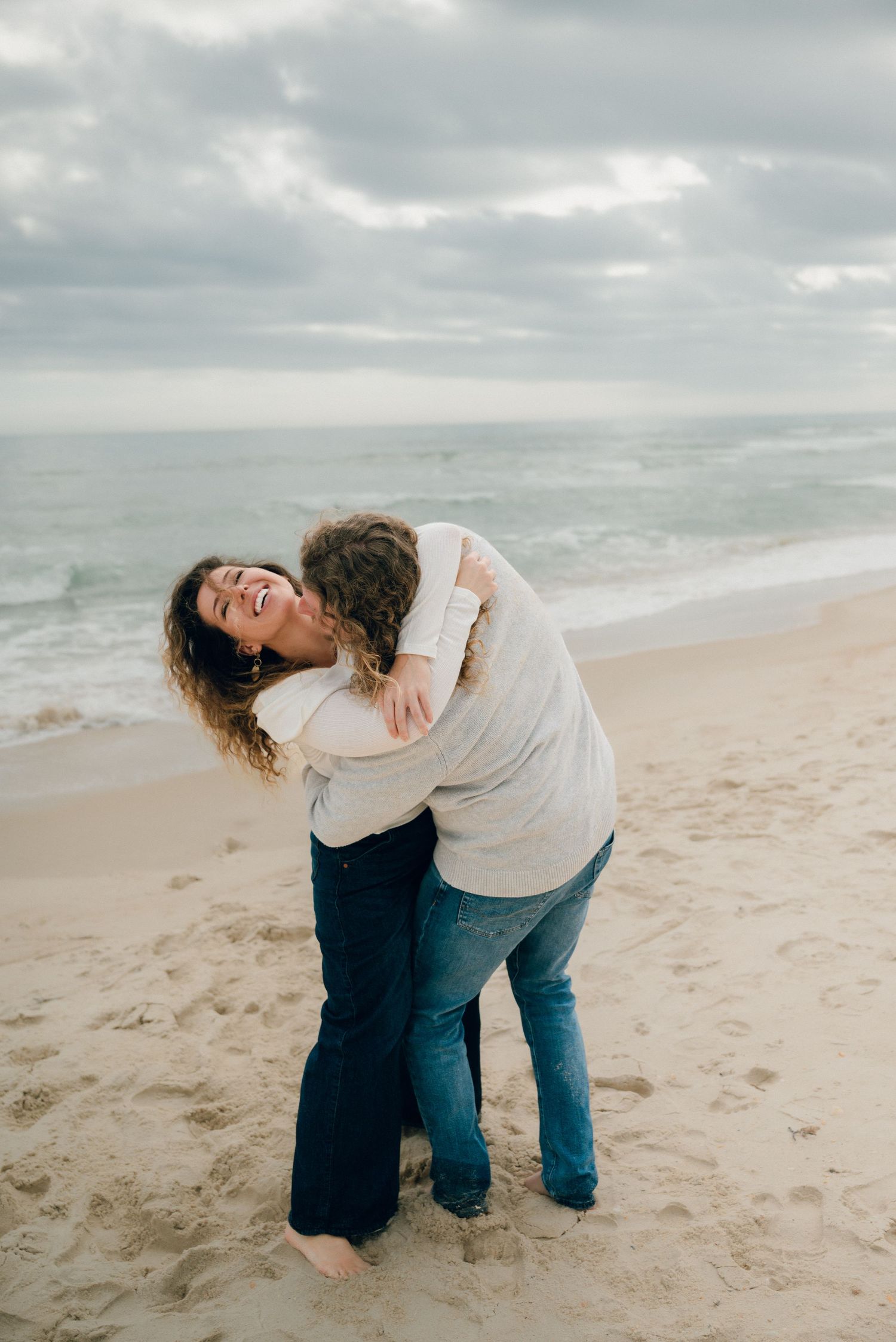 A sequence of playful moments on a cloudy beach as someone bends backwards in a flowing motion on the sand.