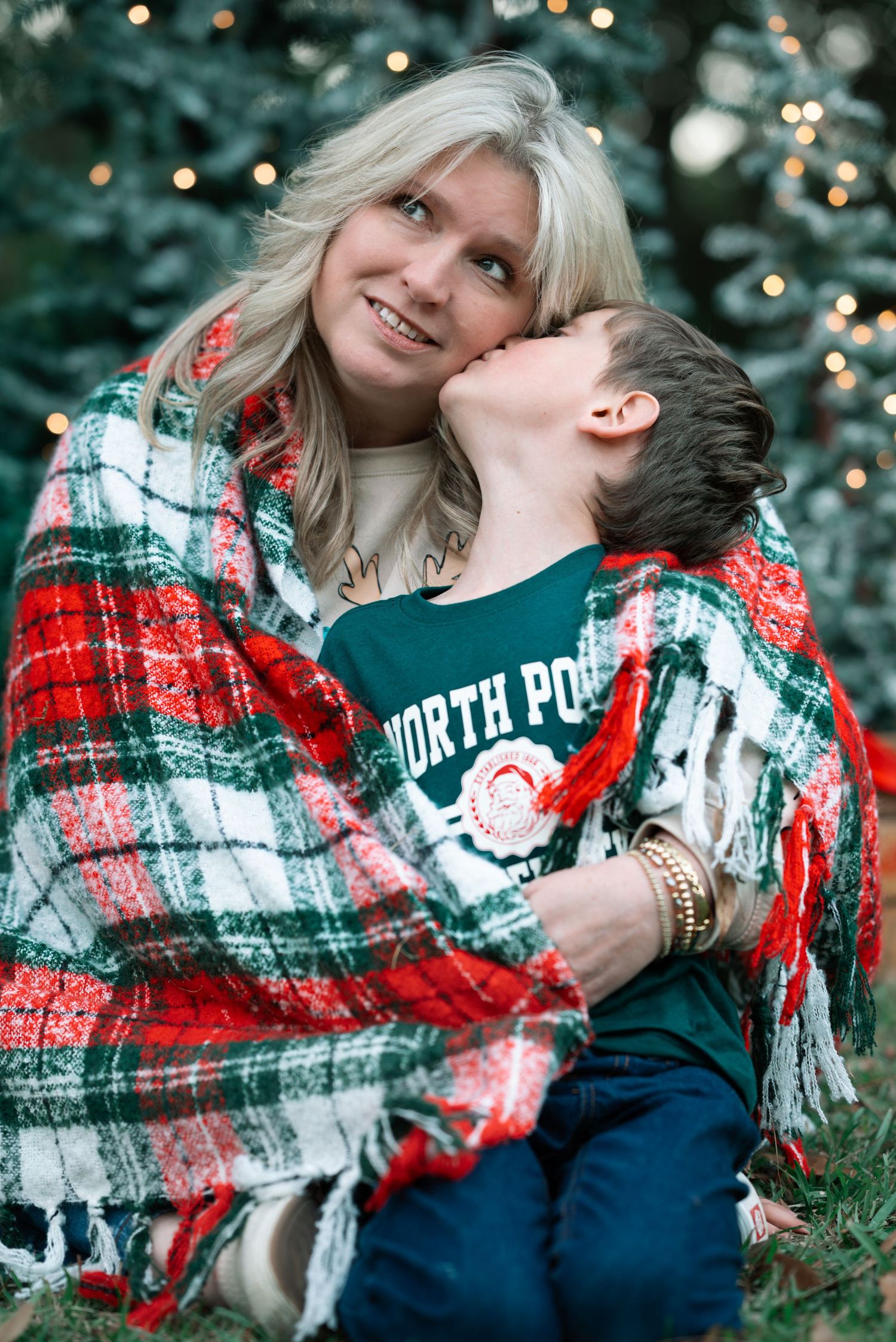 Cozy winter photo session with plaid blanket and festive lights in background.