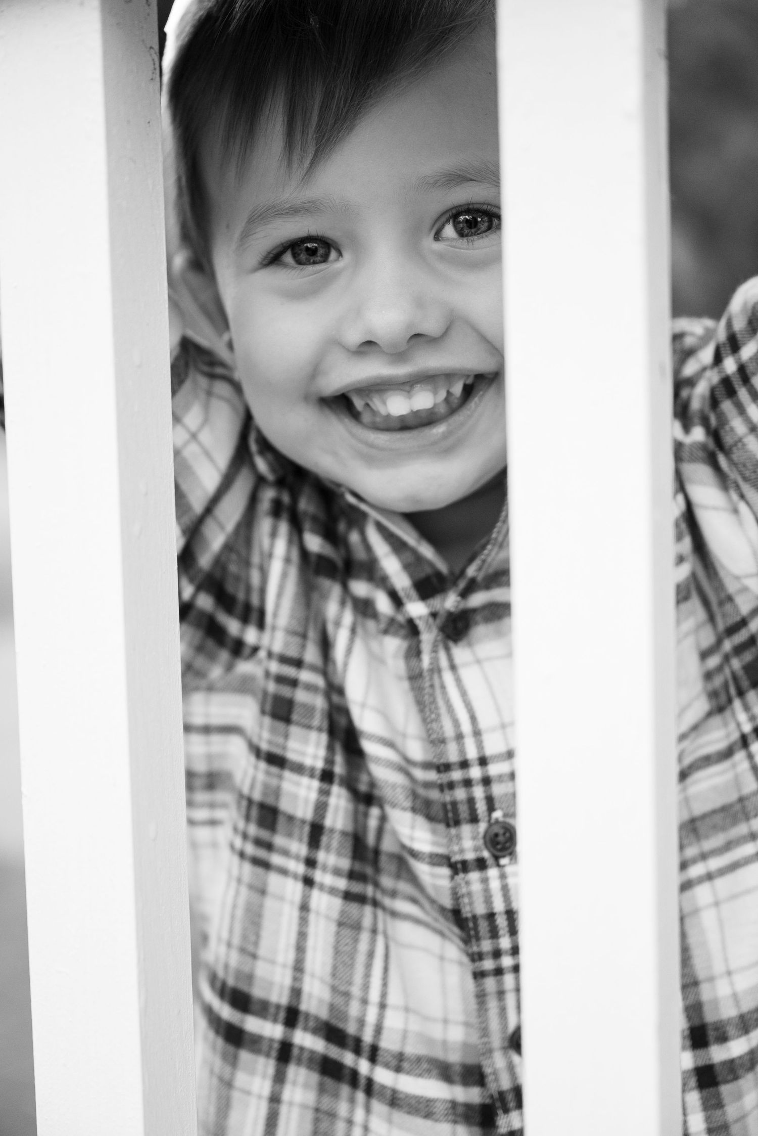 Black and white portrait through white railings showing joyful expressions.