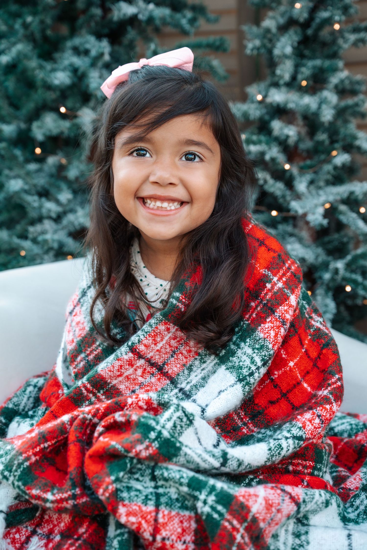 A winter holiday portrait with someone wrapped in a red and green plaid blanket.