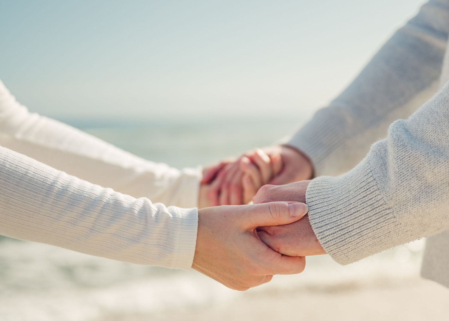 A series of hands reaching out and holding each other in unity against a light background.