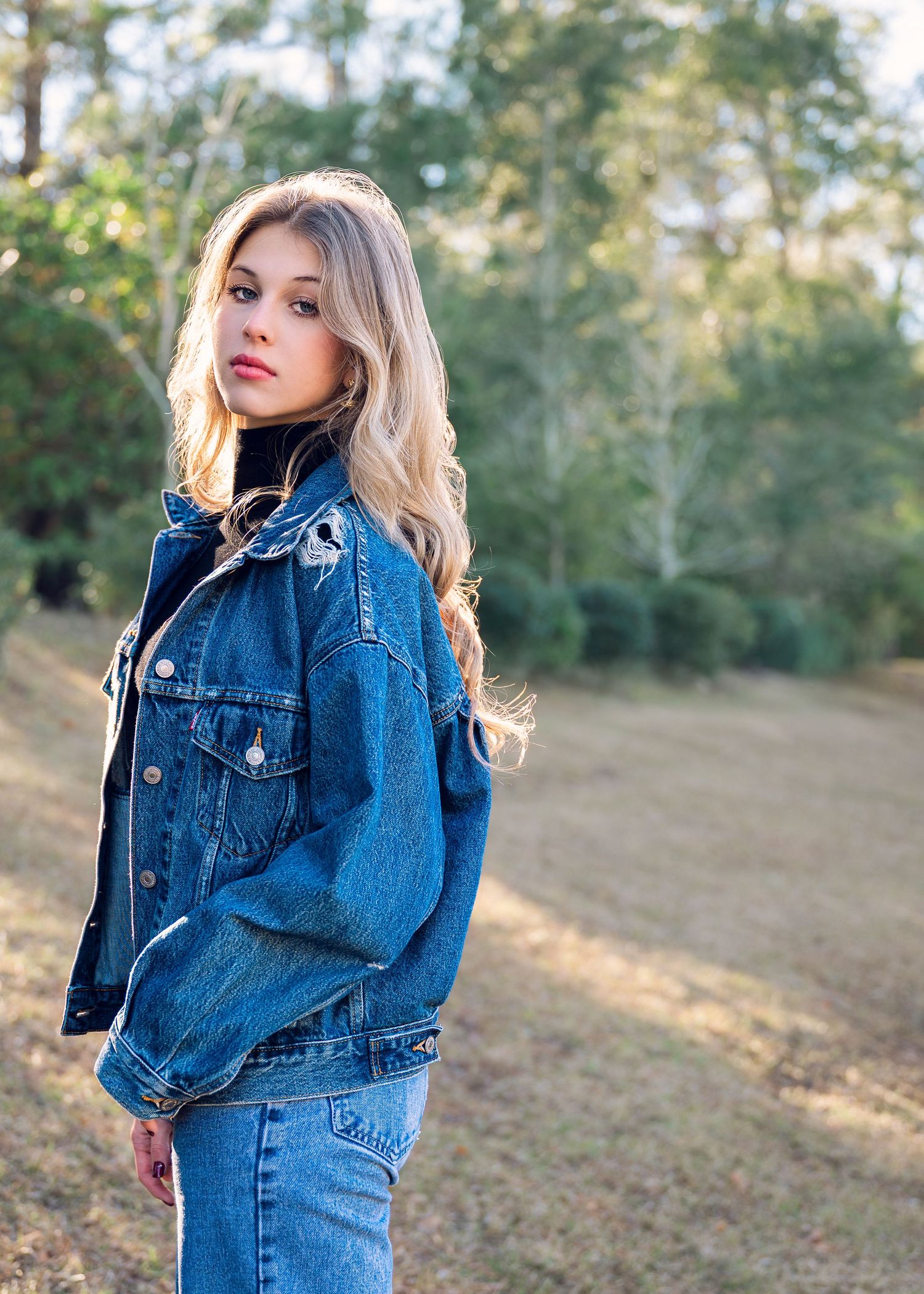 Fashion portrait series featuring denim jacket against natural outdoor setting.