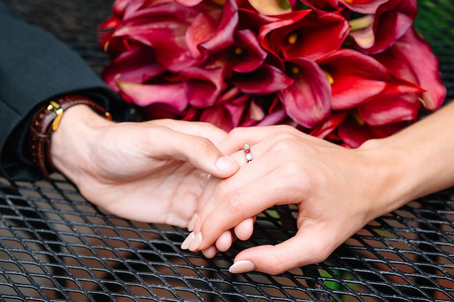 Close-up of manicured hands holding pink flowers against dark background.